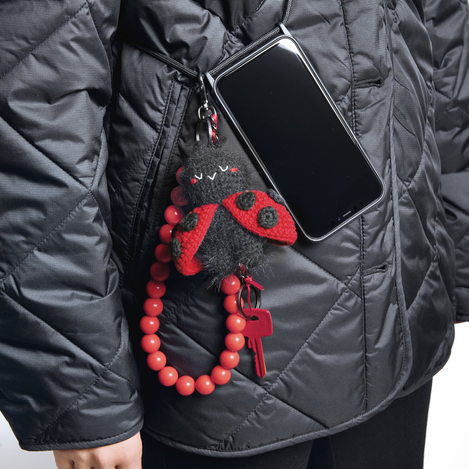 Ricorumi Rico Chingus: Karabiner mit Kette und Schlüsselring, schwarz-rot, an Jacke befestigt.