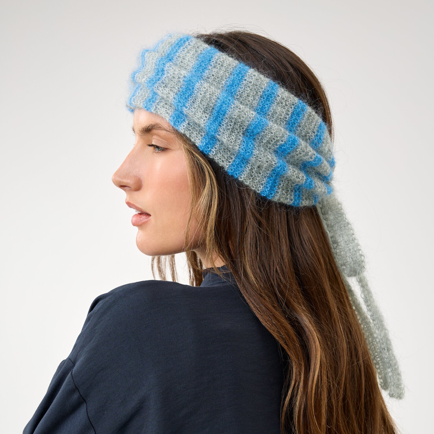 Strickset Schalkragen Modell 21c aus Die Neue Masche No. 16, seitliches Porträt einer Frau mit gestreiftem, flauschigem Stirnband mit langen Bindebändern