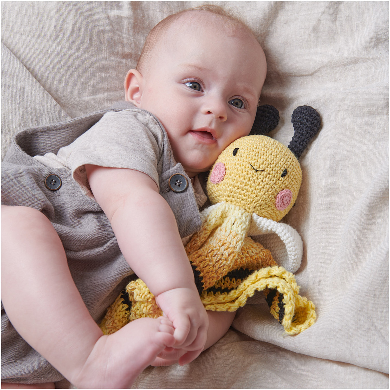 Creative Ricorumi dk: Ein Baby kuschelt mit einer gelben, gehäkelten Bienenpuppe von Rico Design.