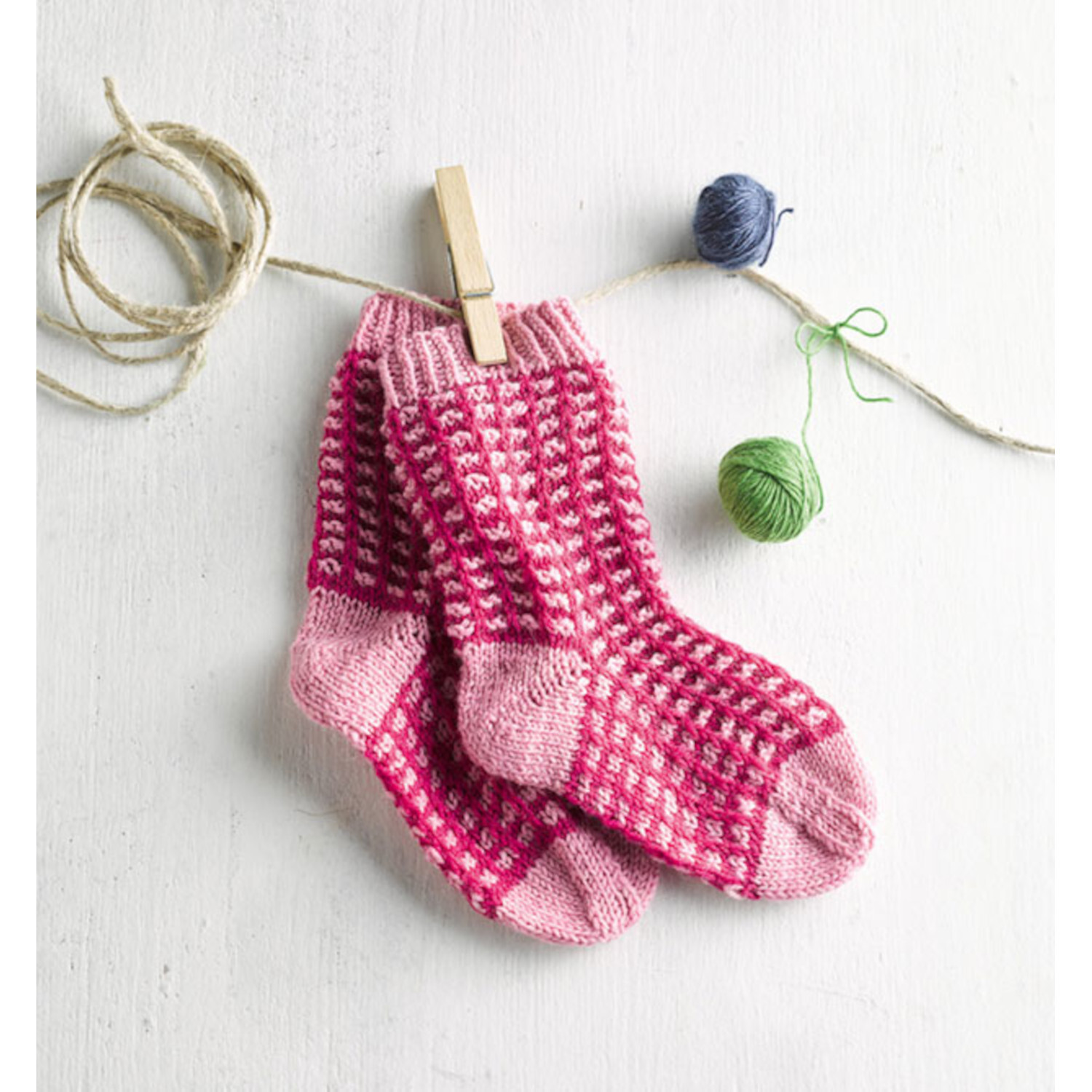 Oh du sockige Weihnachtszeit - Adventskalender: Rosa und rote gestrickte Socken hängen an einer Leine mit Garnknäueln.