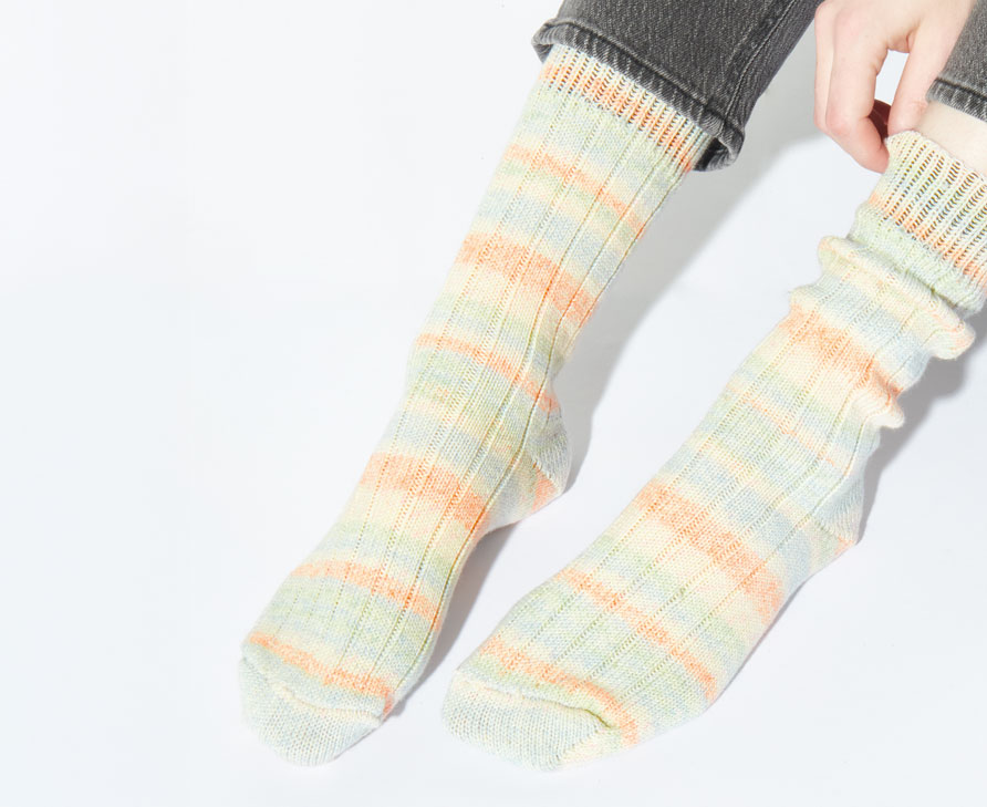Frau trägt pastellfarbene Stricksocken an den Füßen