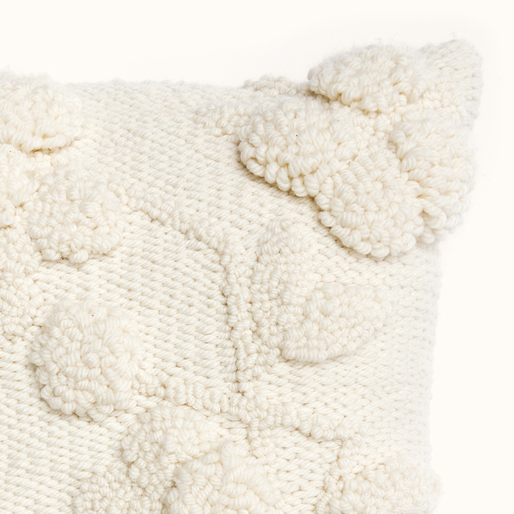 Ecke eines cremefarbigen Kissens mit Punch Needle Stickereien