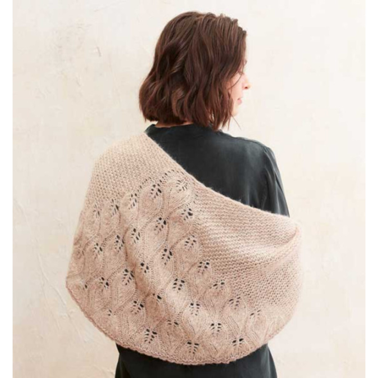 Stricken mit Struktur: Frau trägt ein beiges, strukturiertes Strickschal über schwarzem Oberteil.