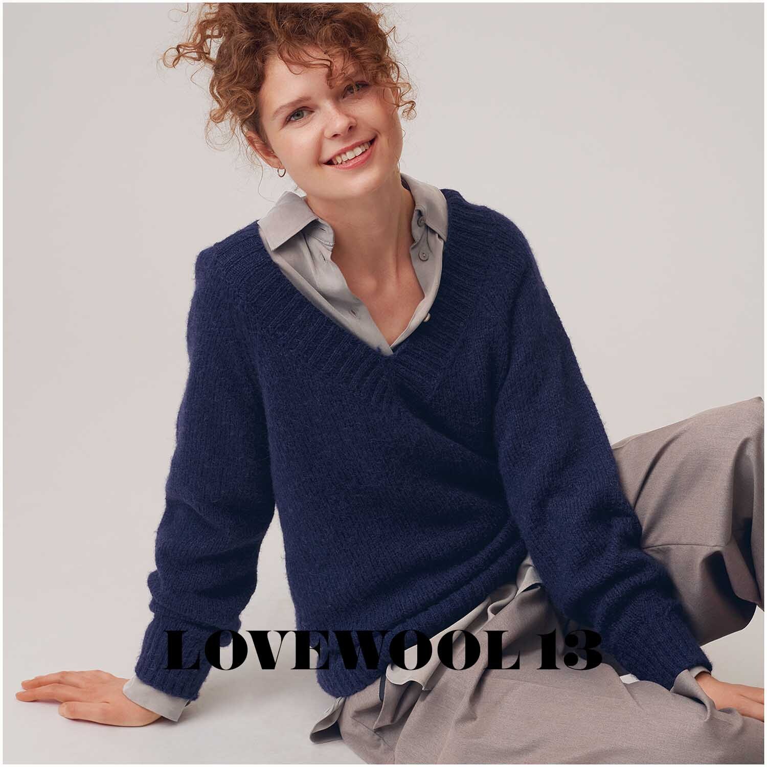 Rico Luxury Alpaca Superfine aran: Frau in marineblauem Pullover von Rico Design, sitzt lächelnd auf dem Boden.