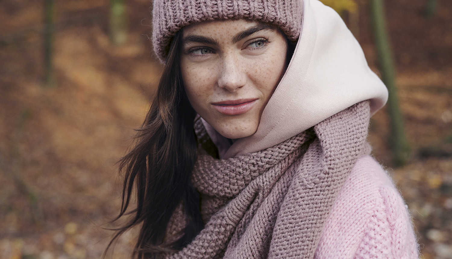 Strickanleitung Dreieckstuch aus Essentials Alpaca Twist chunky: Frau mit rosa Mütze und Schal im herbstlichen Wald.