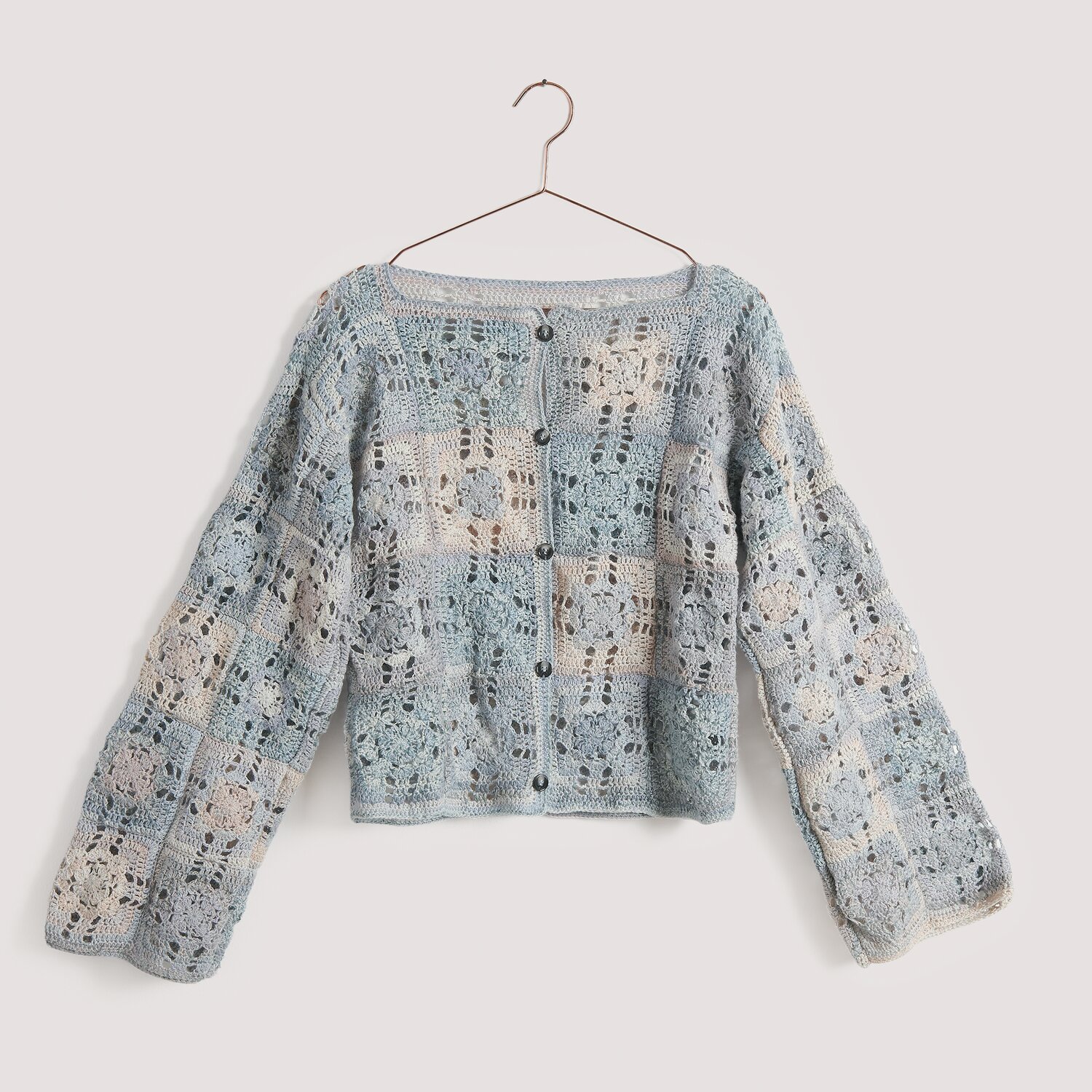 Häkelset Jacke Modell 07 aus Die Neue Masche No. 15, gestrickt in sanften Blautönen mit Knopfleiste, präsentiert auf einem Kleiderbügel.