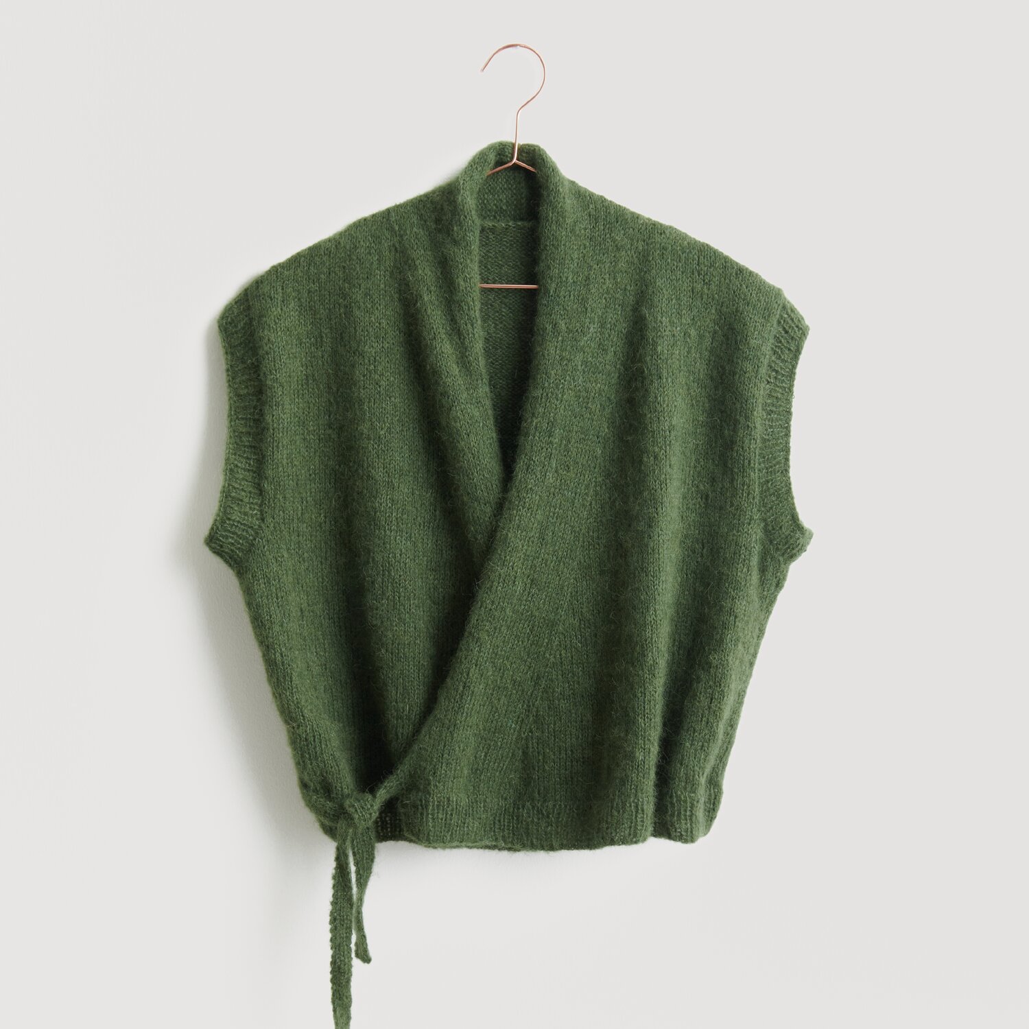 Grüne Strickweste von Modell Legeware, präsentiert auf einem Kleiderbügel. Die Weste hat kurze Ärmel und einen Wickelstil mit Bindeband, ideal für einen lässigen Look.