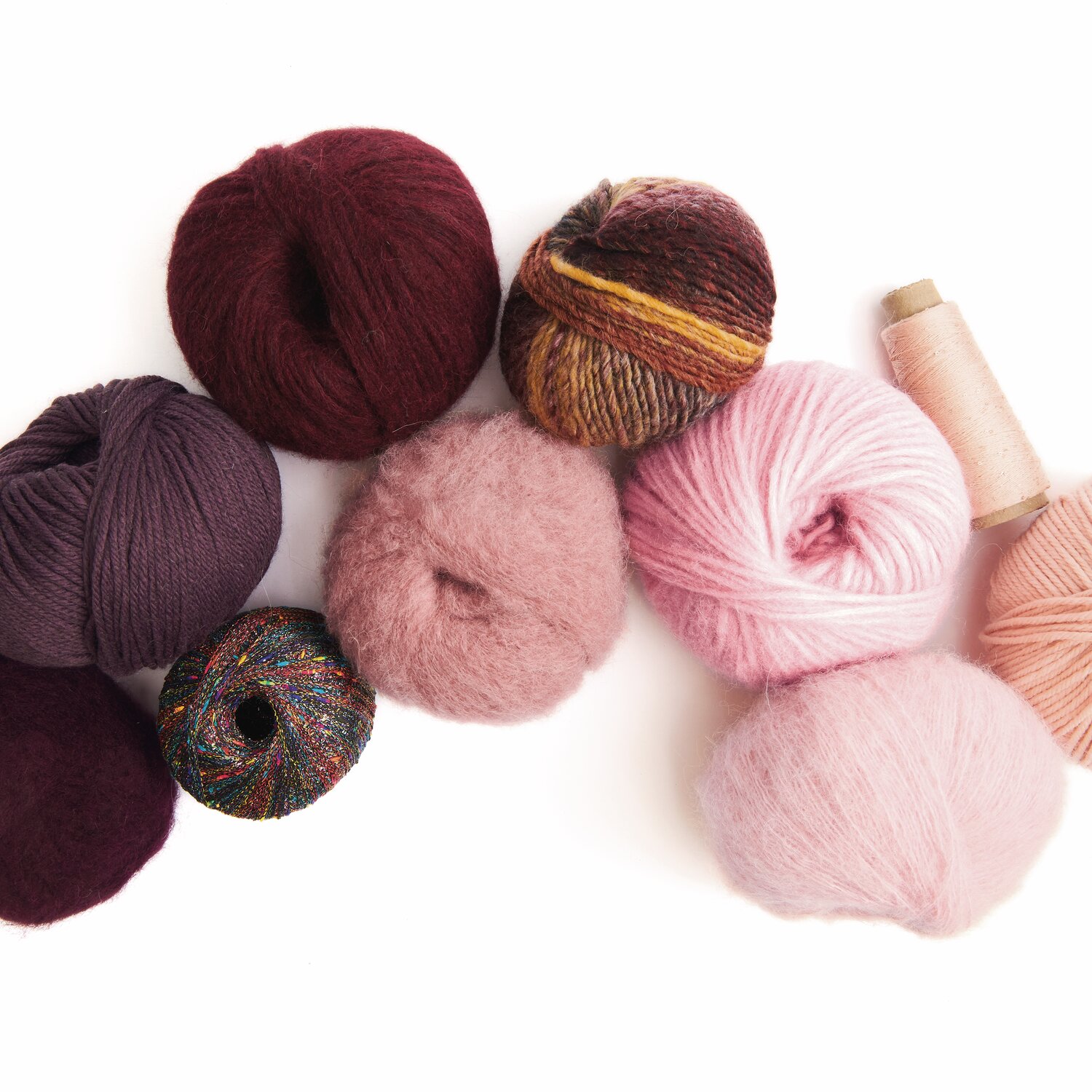 Made by Me No. 21 Herbst-Winter: Verschiedene Wollknäuel in Rosa- und Rottönen, ideal für kreative Strickprojekte.