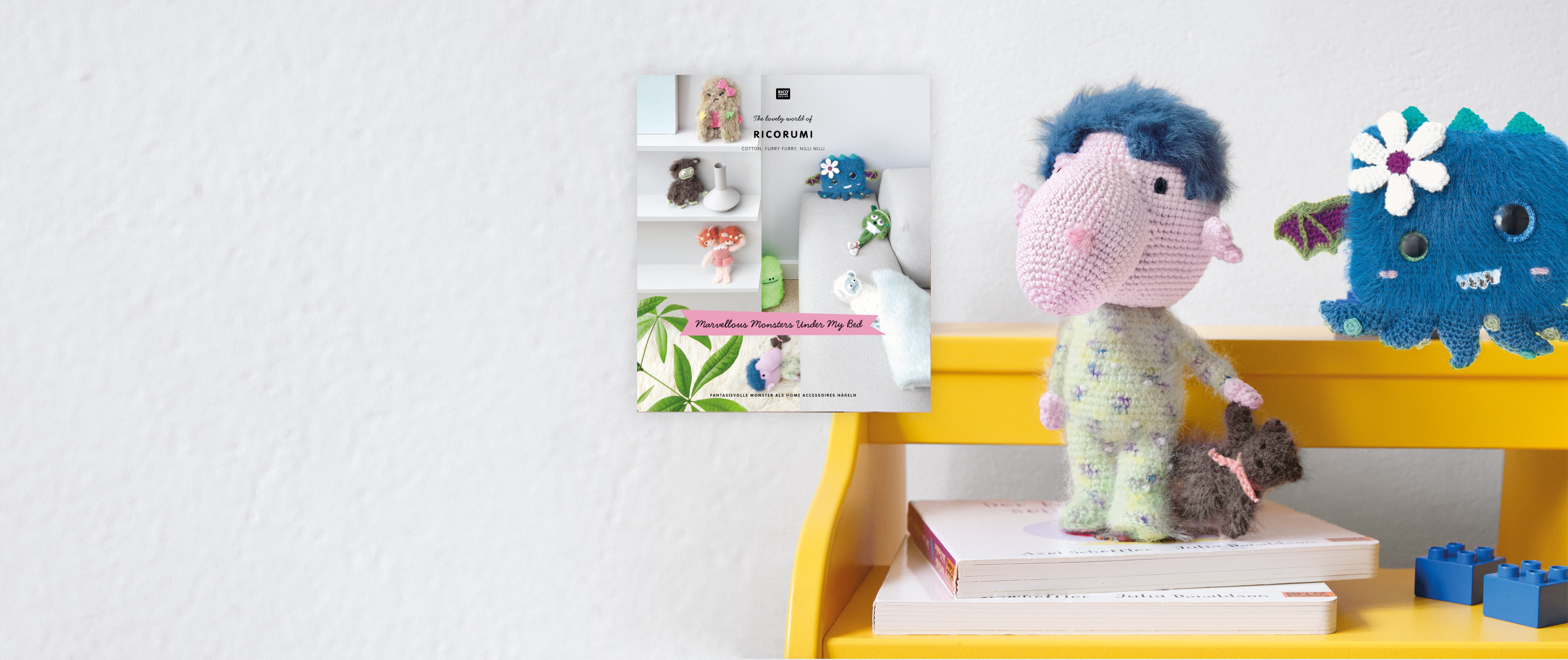 2 gehäkelte Ricorumi Monster stehen auf einer Bank, daneben Anleitungsheft