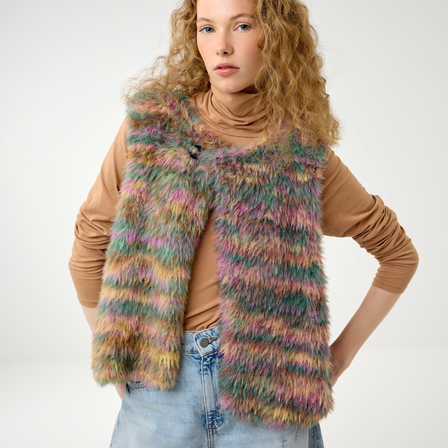 Strickset Weste Modell 9b aus Die Neue Masche No. 16, ärmellose flauschige Damenweste mit mehrfarbigem Streifenmuster, kombiniert mit Rollkragenpullover und Jeans