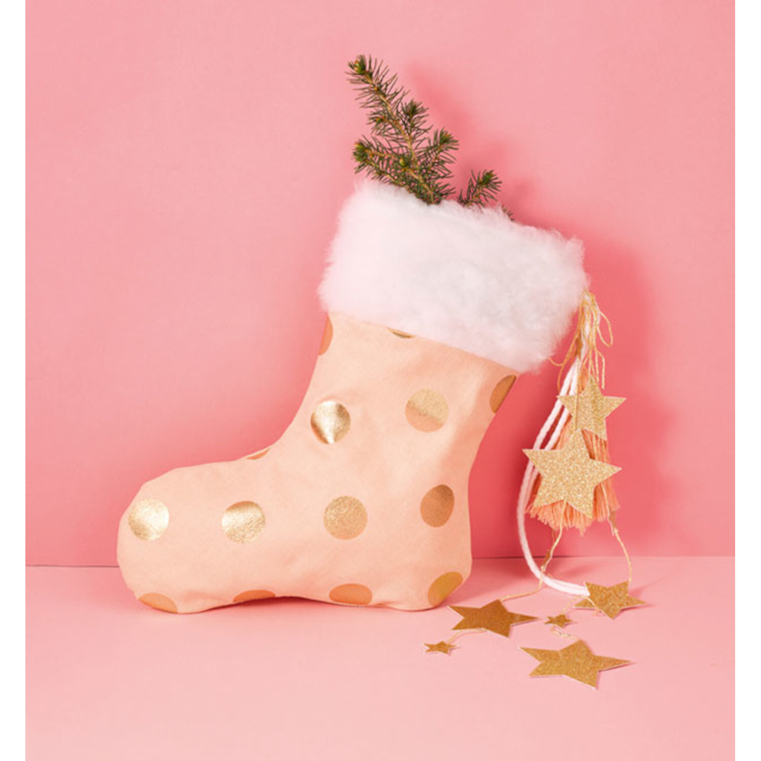Nähen lernen auf Papierbögen: Rosa Weihnachtsstrumpf mit goldenen Punkten und weißen Fellrand, dekoriert mit Sternen und Tannenzweig.
