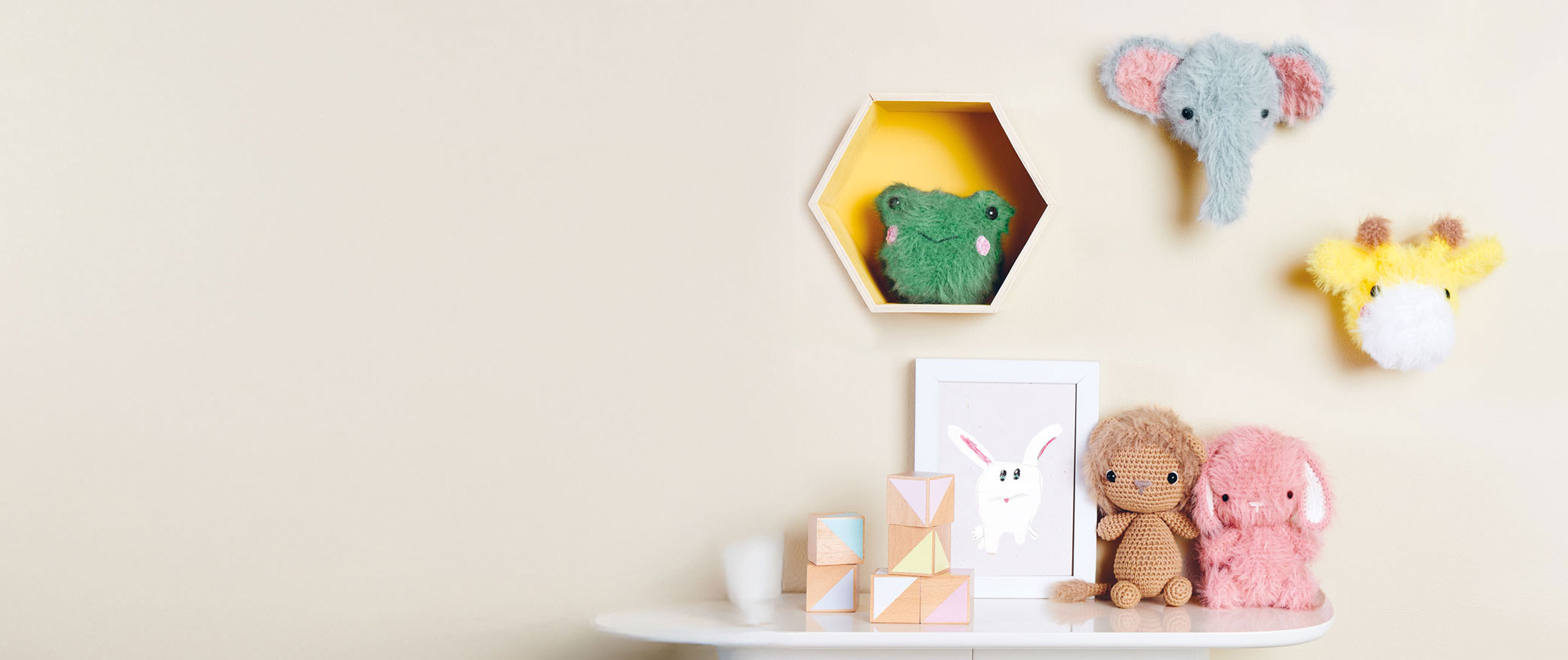 Verschiedene Ricorumi-Häkeltiere hängen an der Wand und sitzen auf einem Tisch