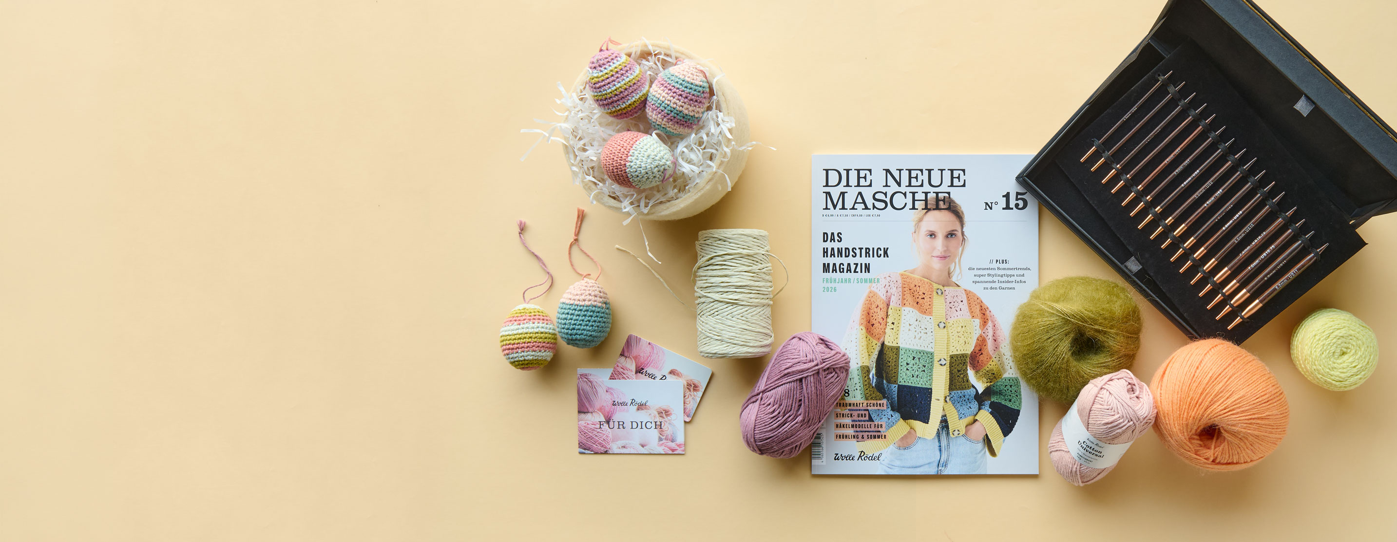Anleitungsheft, Stricknadelset, Geschenk-Karte und Wolle auf gelbem Hintergrund