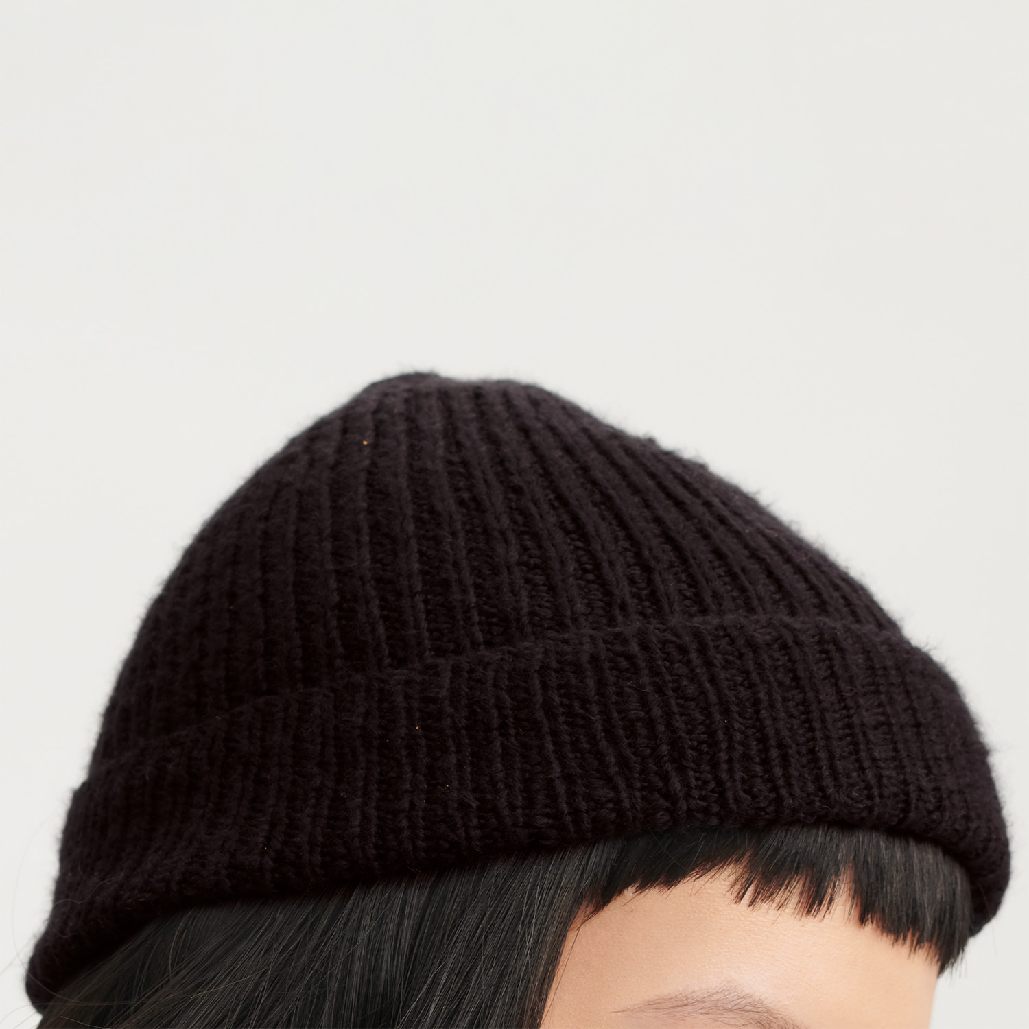 Strickanleitung Mütze aus Fashion Cottony: Schwarze, gerippte Mütze auf einem Kopf, ideal für kalte Tage.