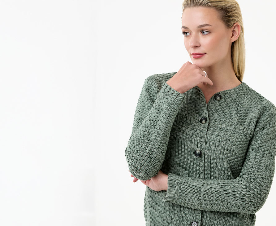 Frau trägt grüne Strickjacke vor einem neutralen Hintergrund