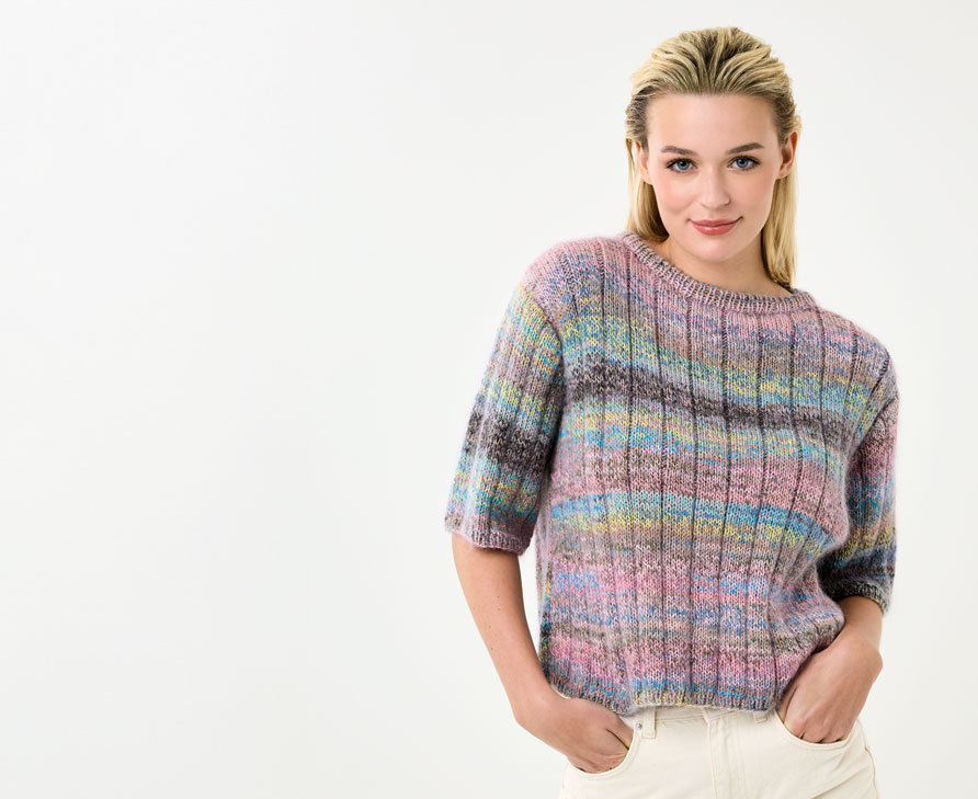Model trägt Stricktop mit bunten Streifen vor einem hellen Hintergrund.