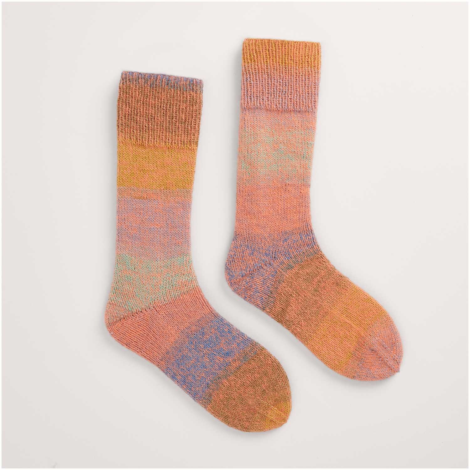 Buntes Strickset für Socken, Modell 45 aus Made by Me Nr. 17. Die Socken zeigen ein harmonisches Farbspiel aus Orange, Rosa und Blau. Perfekt für kreative Strickprojekte.
