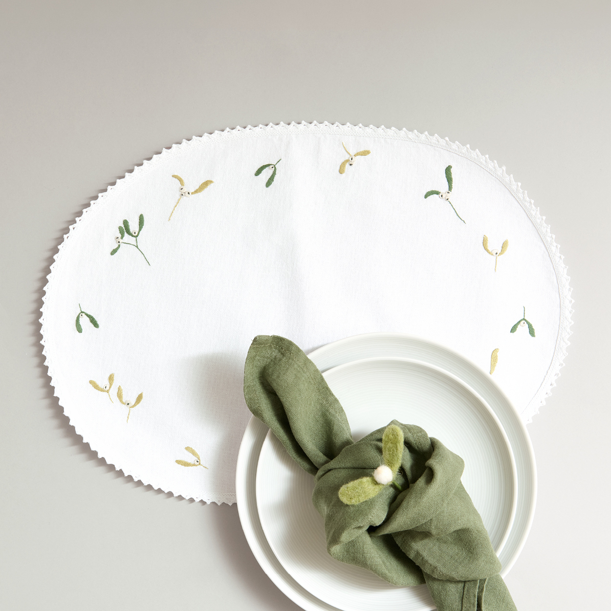 Teller mit gesticktem Deckchen und mit grüner Serviette