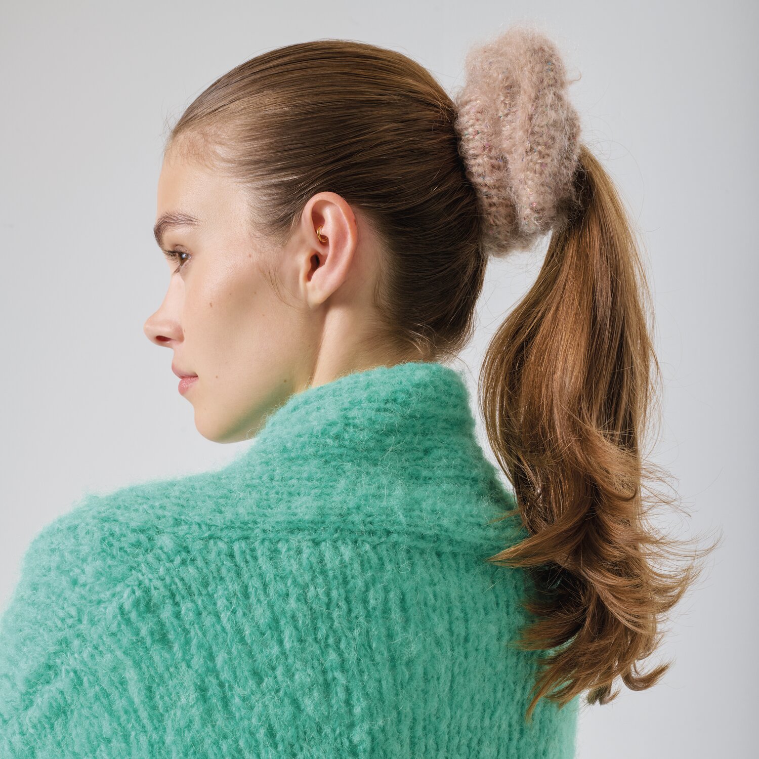 Strickset Scrunchie Modell 18a: Frau mit beigem Scrunchie im Haar, trägt mintgrünen Pullover.
