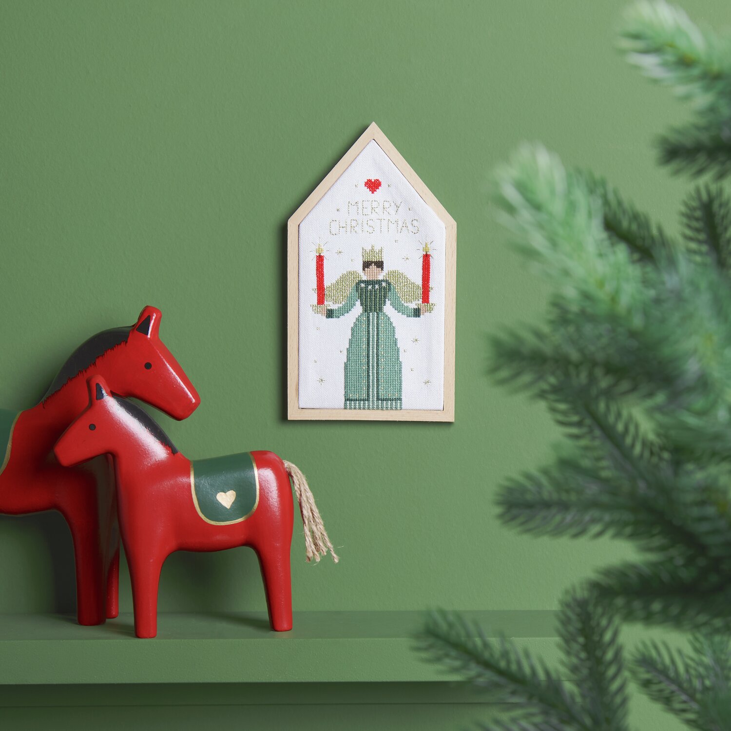 Stickpackung Engel 12,5x22,5cm von Rico Design Stickpackung Engel von Rico Design zeigt einen gestickten Engel mit Kerzen, eingerahmt an grüner Wand.