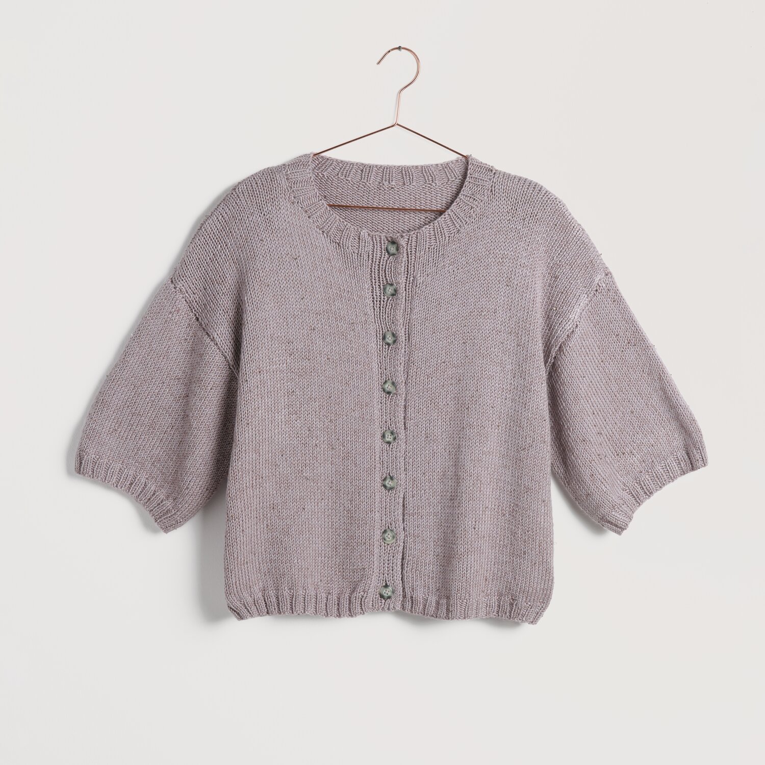 Strickset kurzarm Jacke Modell 11 in Amethyst, aus Lovewool No. 22, auf einem Kleiderbügel.