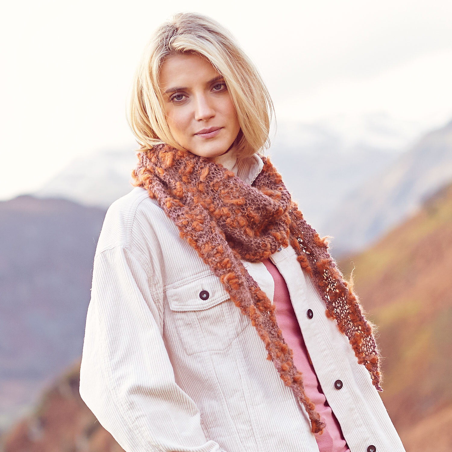 Strickanleitung Dreieckstuch aus Fashion Alpaca Vibes: Frau trägt ein gestricktes, braunes Dreieckstuch in alpiner Landschaft.