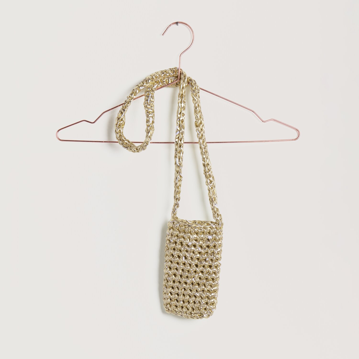 Häkelset Tasche Modell 24 aus Lovewool No. 22: Goldene, gehäkelte Tasche an einem Kleiderbügel. Ideal für Frühjahr-Sommer.