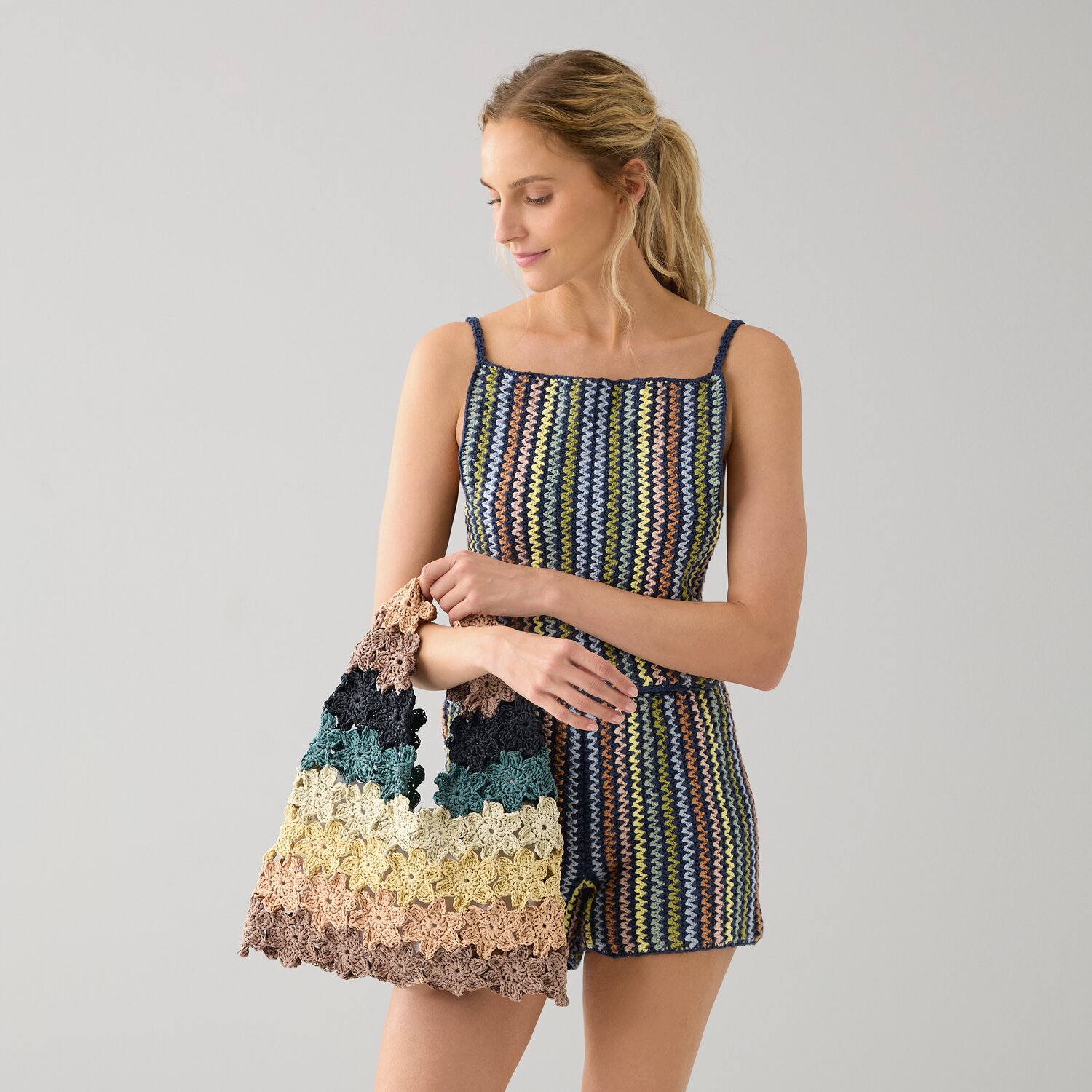 Häkelset Tasche Modell 05 A, bunte Streifen, Frau hält Tasche, passend zum gestreiften Outfit.