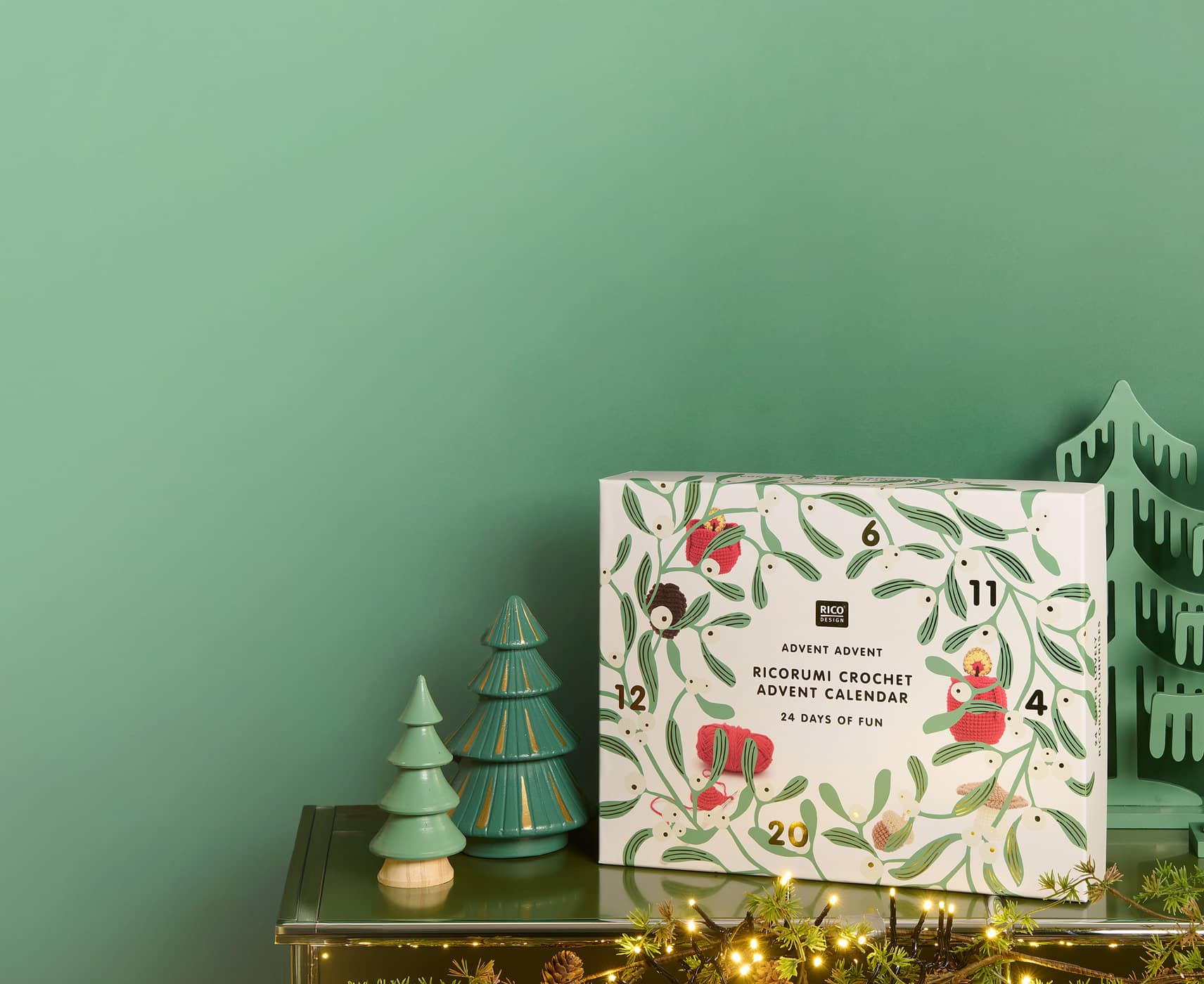 Ricorumi Adventskalender steht auf Kamin, daneben dekorative Bäume