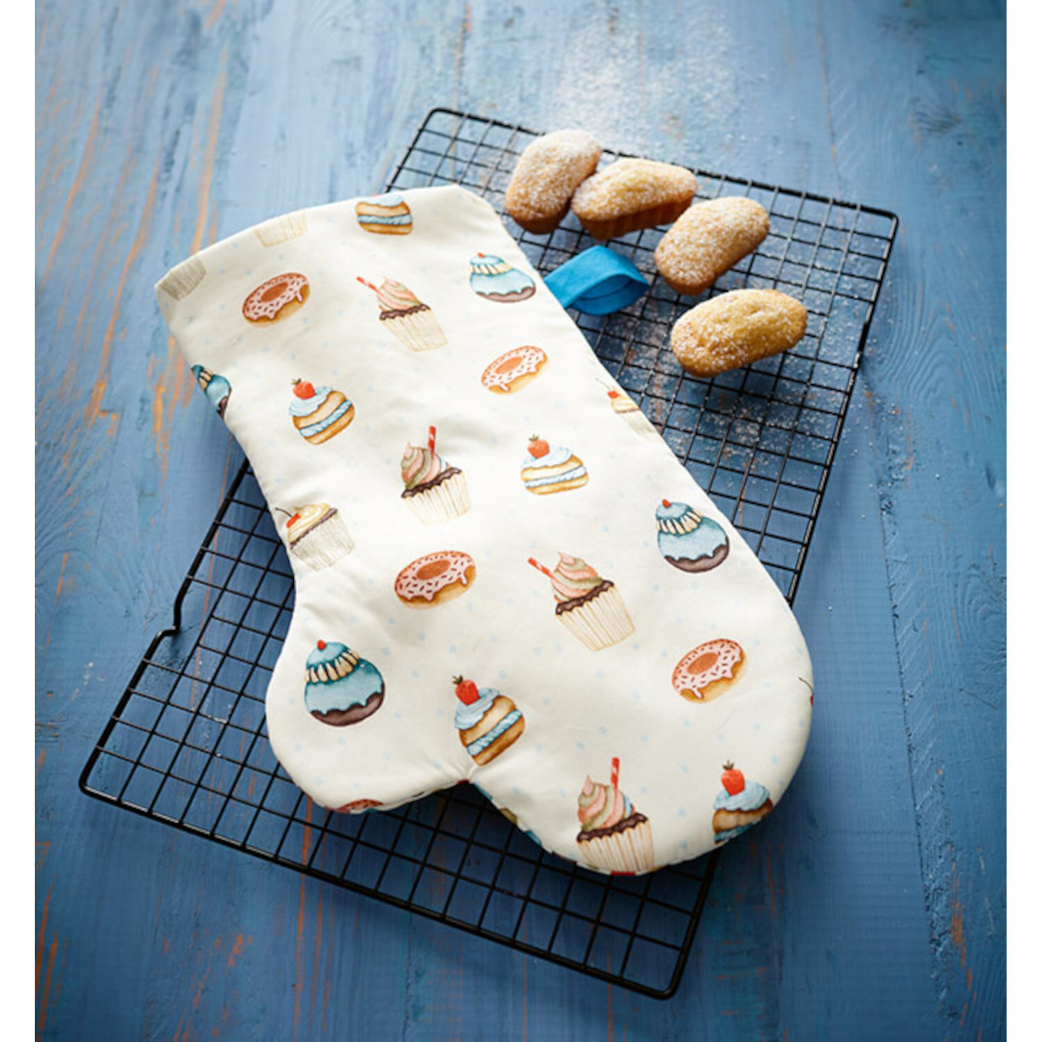 Näh-Quickies: 15-Minuten-Projekte. Weißer Ofenhandschuh mit buntem Cupcake-Muster auf blauem Holztisch.