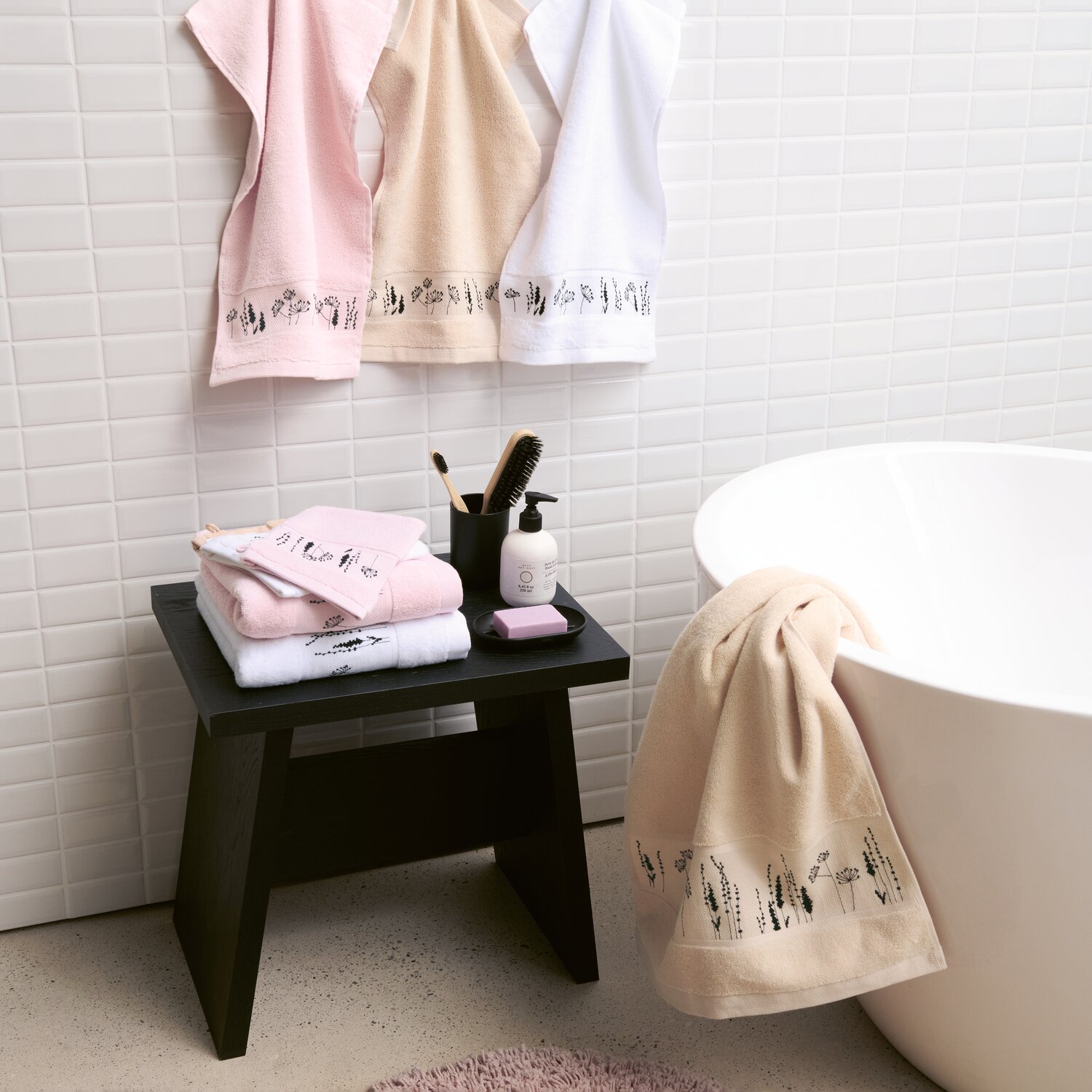 Stickset Gästetuch, Puder Modell 80857 aus Stickbuch 186 zeigt bestickte Gästetücher auf Handtuchhalter in modernem Badezimmer mit heller Wand und Badewanne.