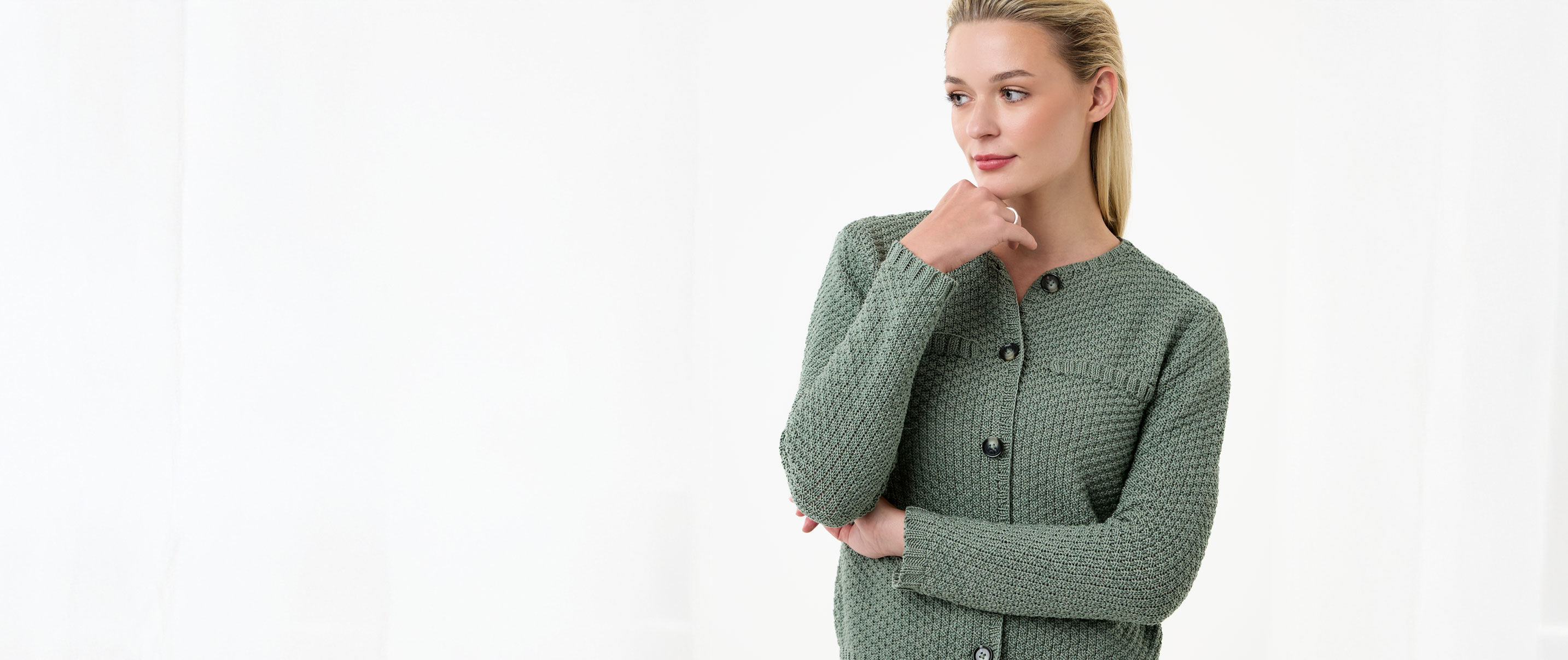 Frau trägt grüne Strickjacke vor einem neutralen Hintergrund
