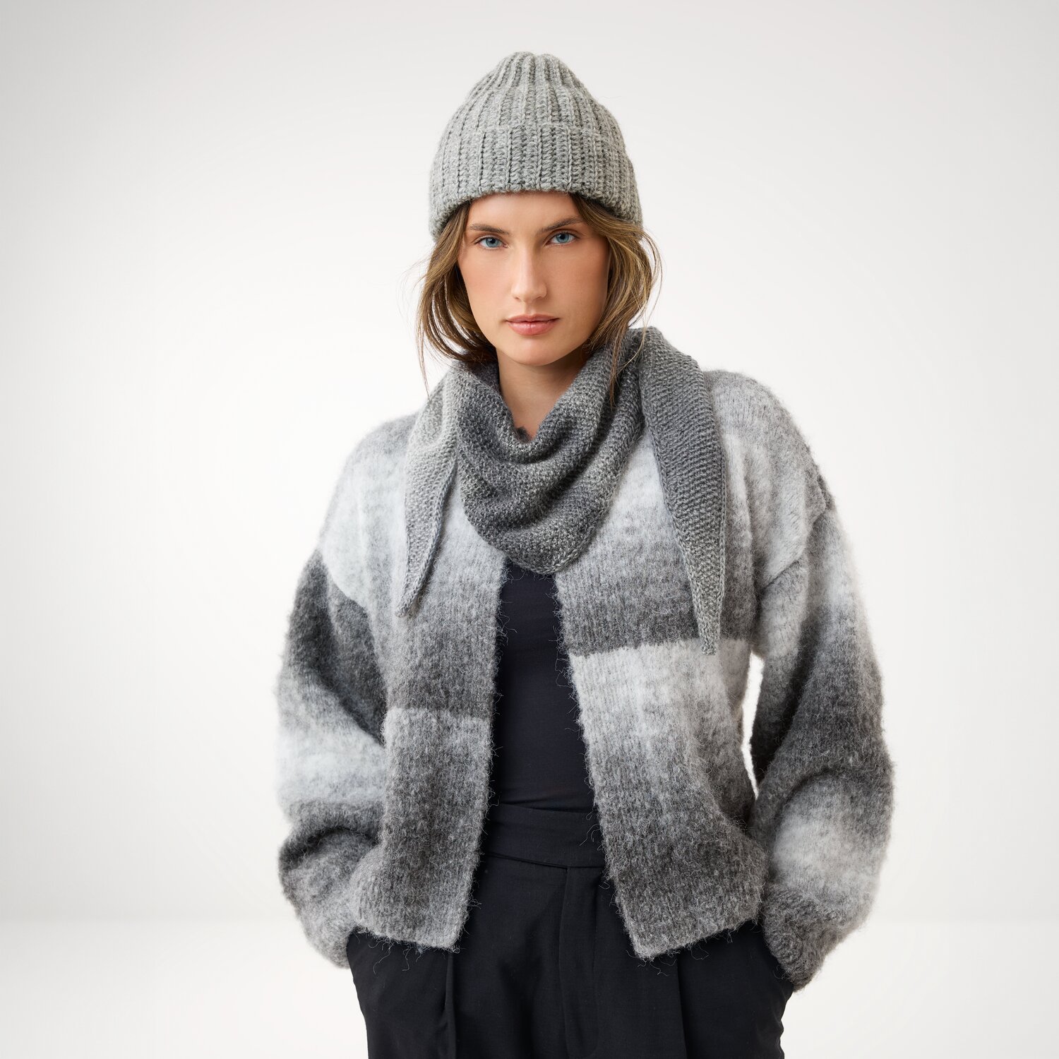 Häkelset Mütze Modell 03 aus Die Neue Masche No. 16, passend zum Strickset Minituch Modell 04, getragen von Frau mit melierter Strickjacke