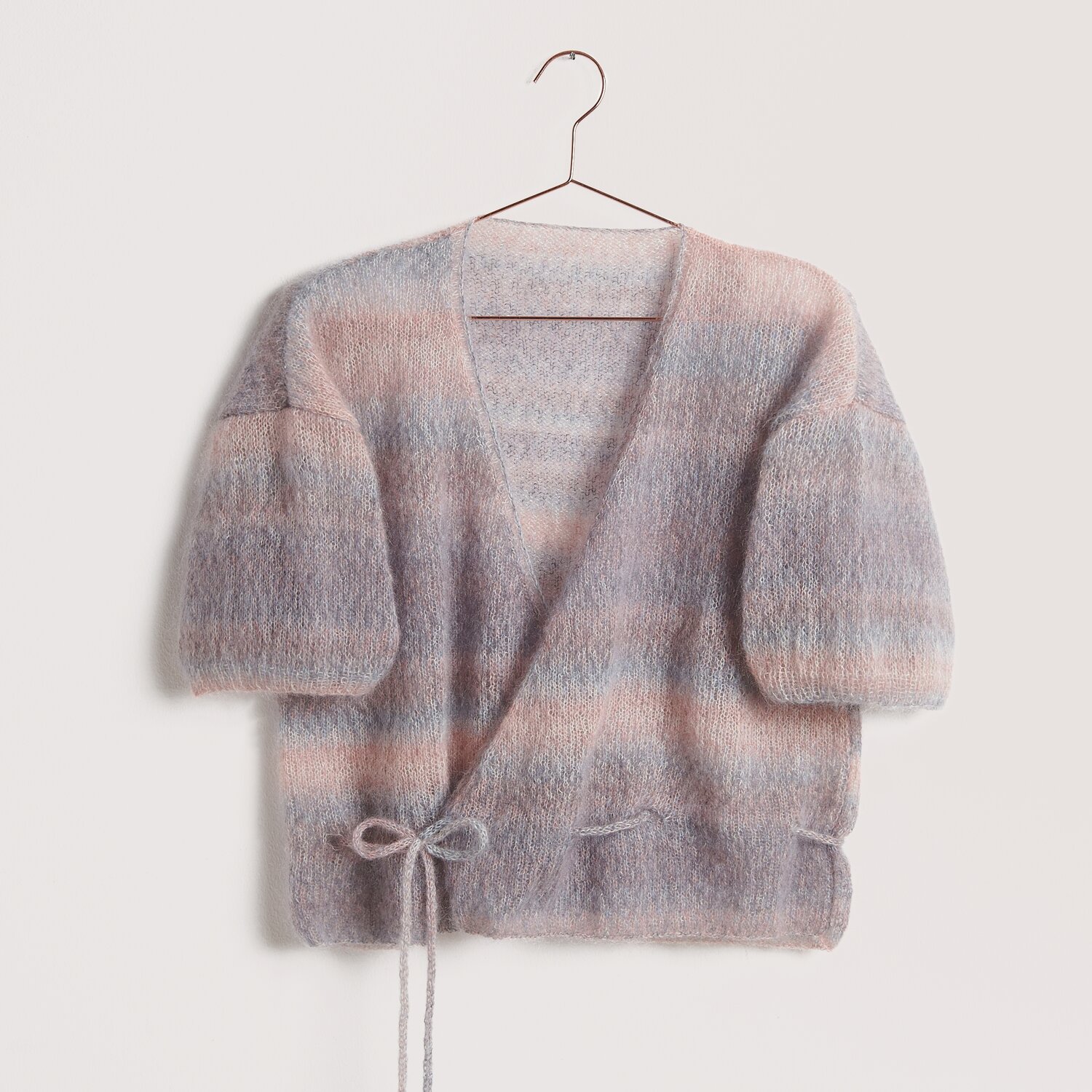 Strickset Pullover Modell 07b aus Die Neue Masche No. 12 von idee. Creativmarkt Die Neue Masche No. 12: Weiche Strickjacke aus Super Kid Mohair in Pastelltönen, auf einem Bügel.