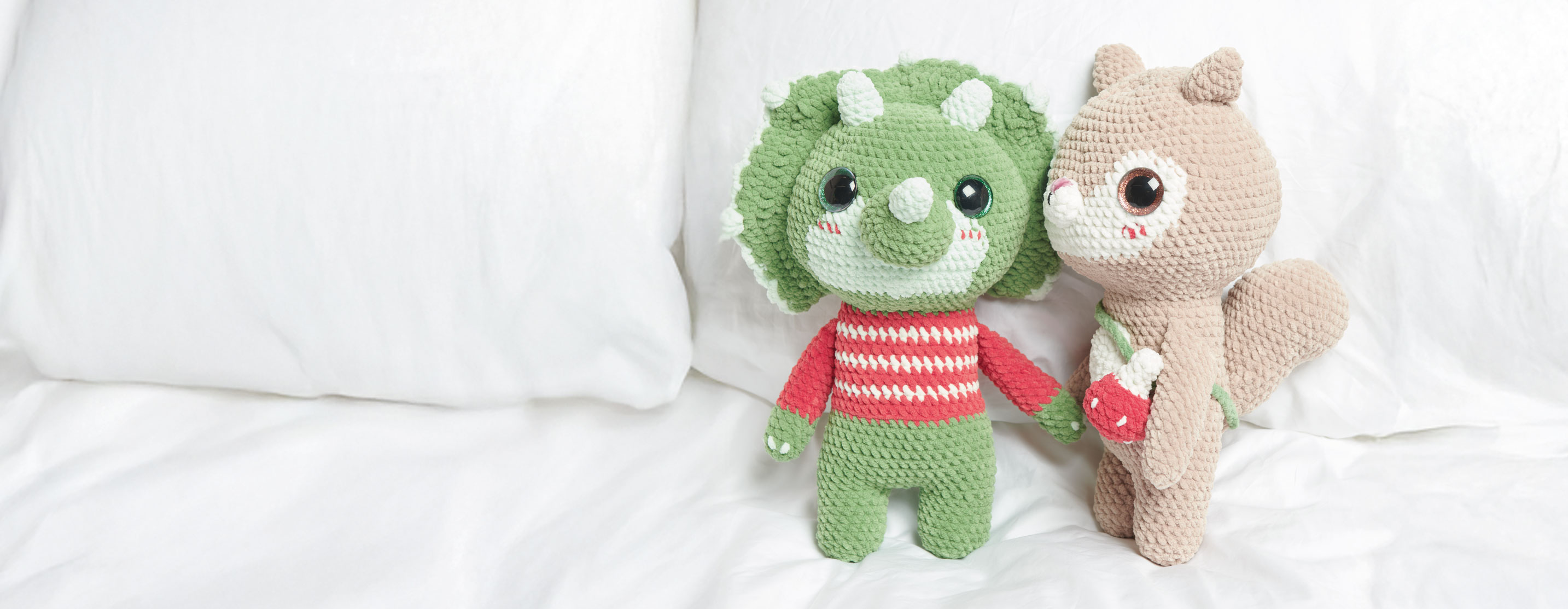 Gehäkelter Dinosaurier und gehäkeltes Eichhörnchen sitzen auf einem Bett