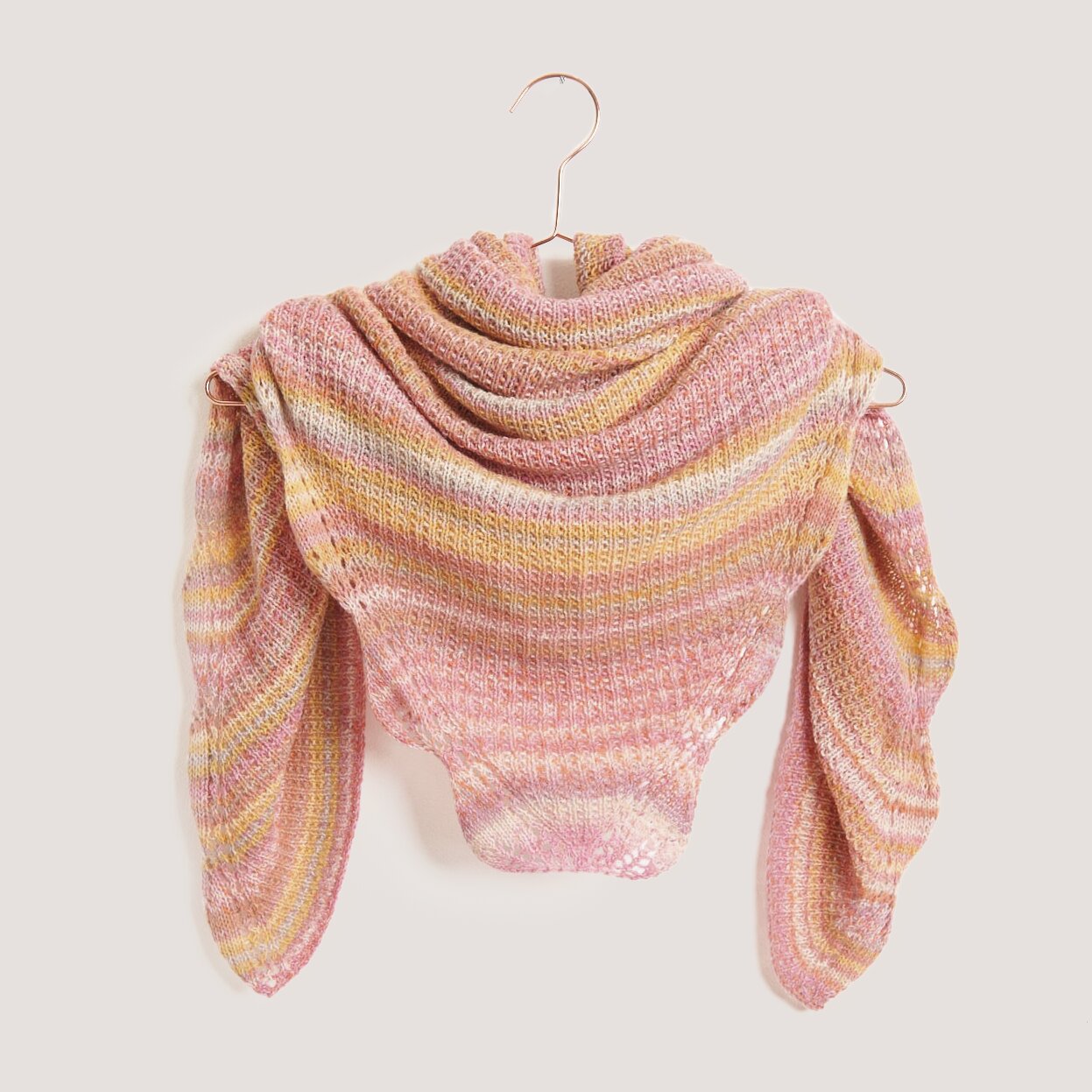 Strickset Dreieckstuch Modell 06 aus Tücher Special von Rico Design Strickset Dreieckstuch Modell 06 aus Tücher Special in Pastel, präsentiert auf einem Kleiderbügel. Ideal für modische Strickprojekte.