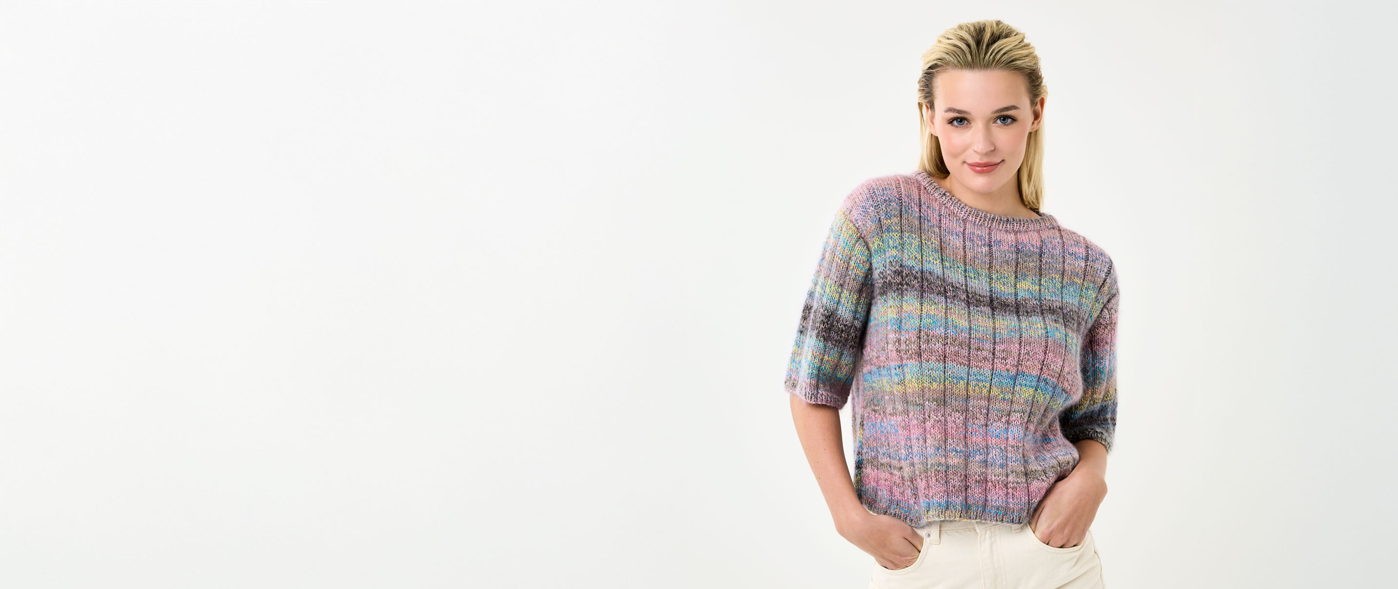 Model trägt Stricktop mit bunten Streifen vor einem hellen Hintergrund.