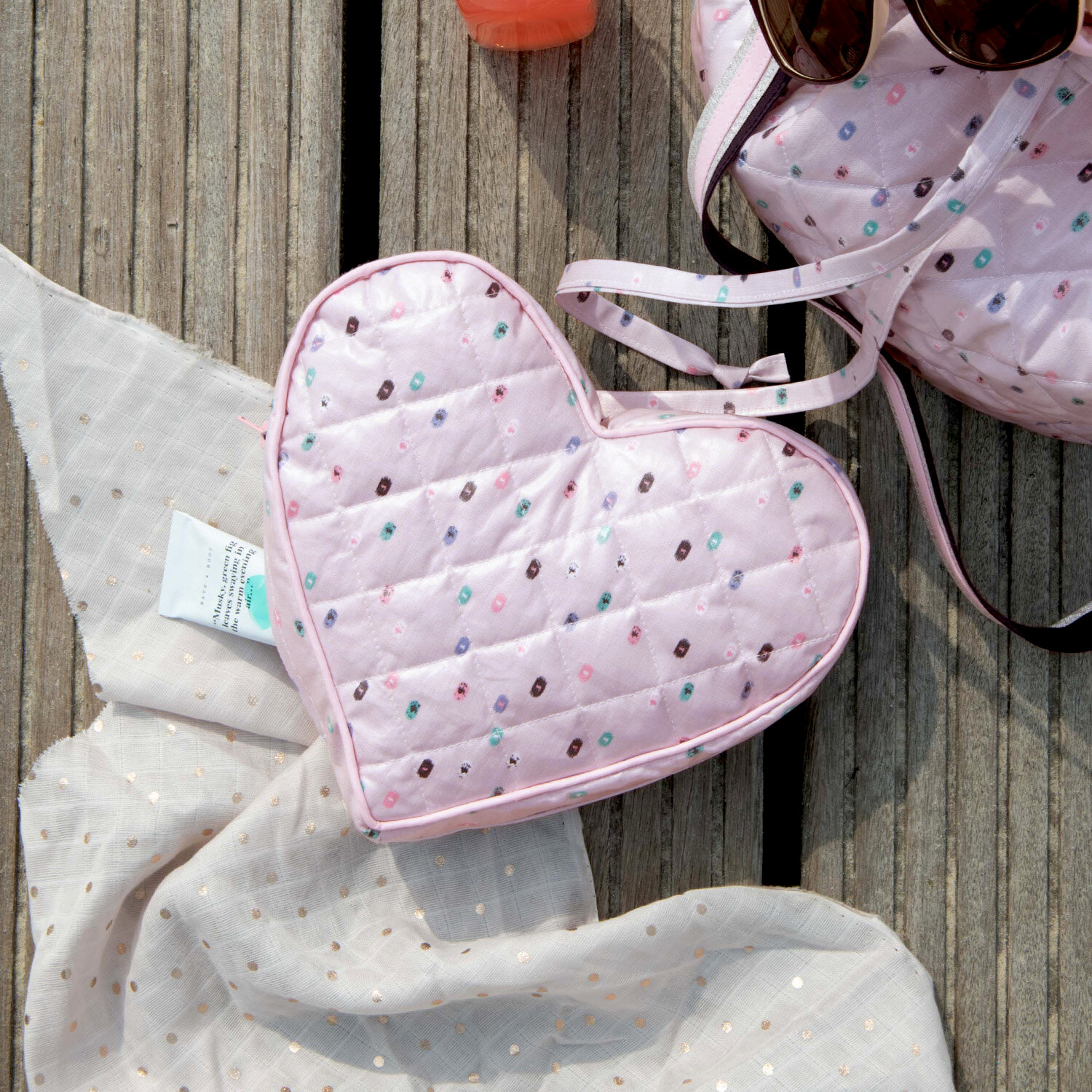 Nähanleitung Clutch in Herzform: Rosa, herzförmige Clutch mit bunten Punkten auf Holzuntergrund.