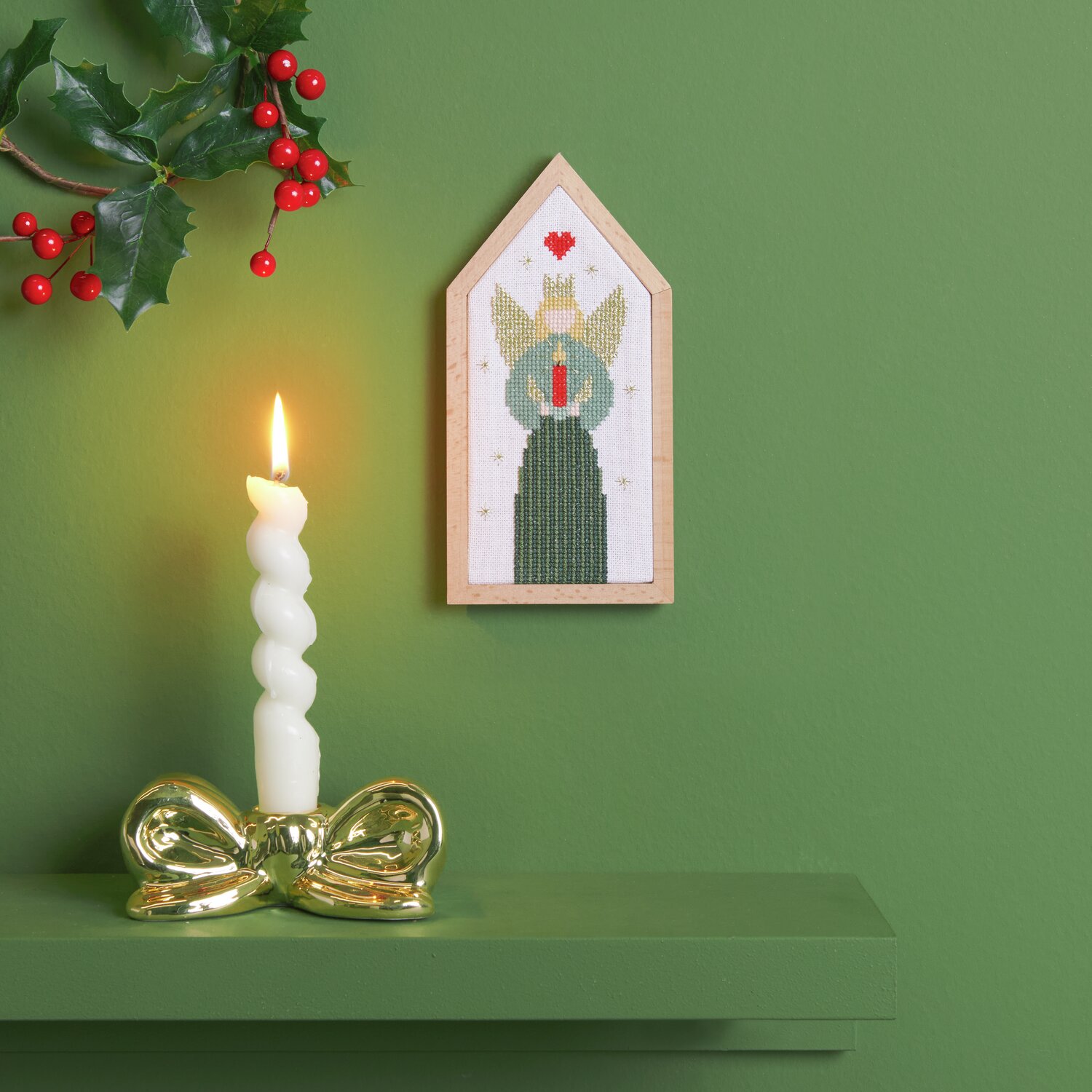 Stickpackung kleiner Engel 9x18cm von Rico Design Stickpackung kleiner Engel von Rico Design: Ein gestickter Engel in Holzrahmen neben einer brennenden Kerze auf grünem Hintergrund.