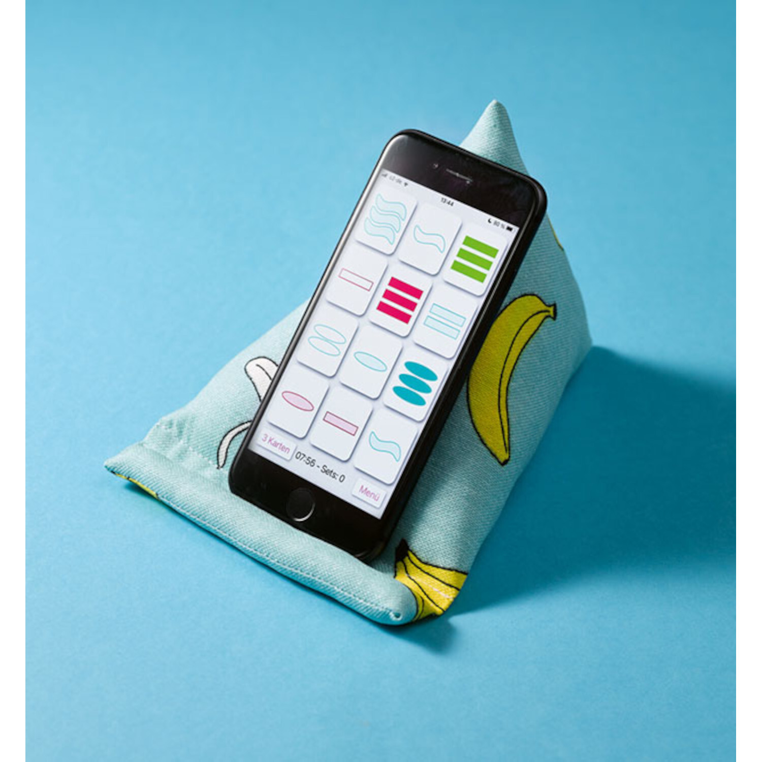 Nähen lernen auf Papierbögen: Smartphone auf blauem Kissen mit Bananenmuster, ideal zum Nähen üben.