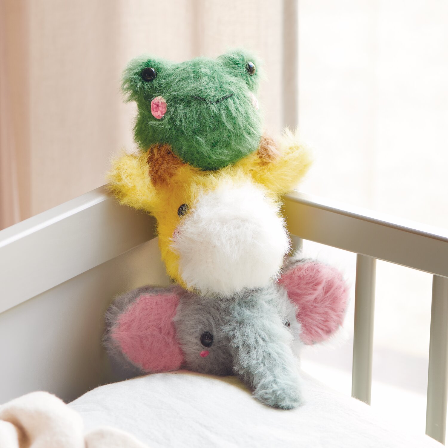 Creative Ricorumi dk 25g Farbe Patina von Rico Design Ricorumi Furry Animals: Flauschige Stofftiere in Grün, Gelb und Grau mit Sicherheitsaugen auf einem Kinderbett.