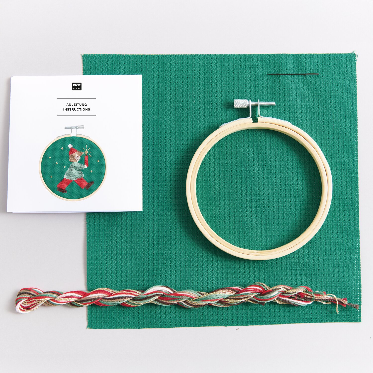 Stickpackung Lichterkind: Grüner Stoff, Holzrahmen, bunte Fäden und Anleitung von Rico Design.