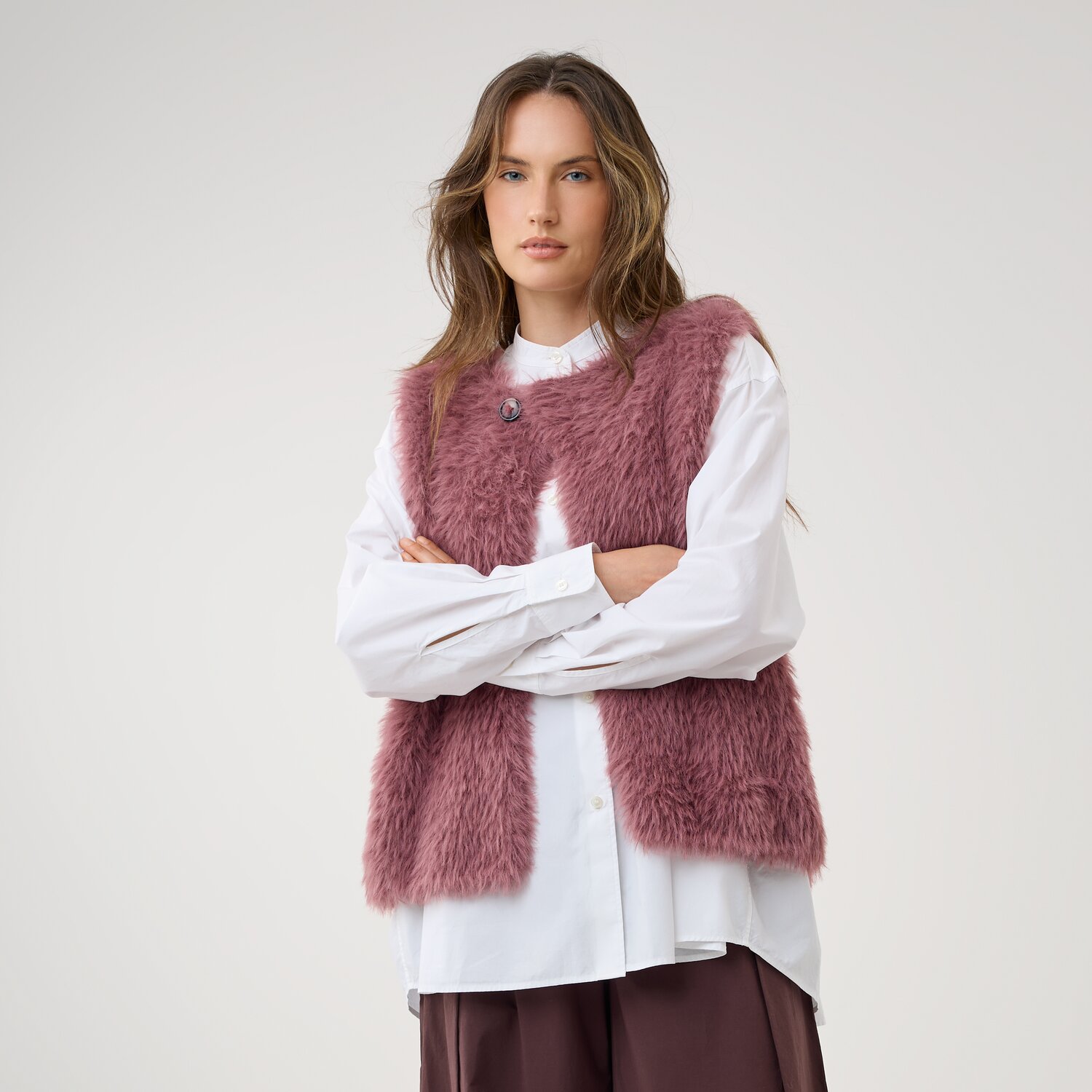 Strickset Weste Modell 9a aus Die Neue Masche No. 16 zeigt eine flauschige, ärmellose Damenweste in Altrosa über weißer Bluse vor neutralem Hintergrund