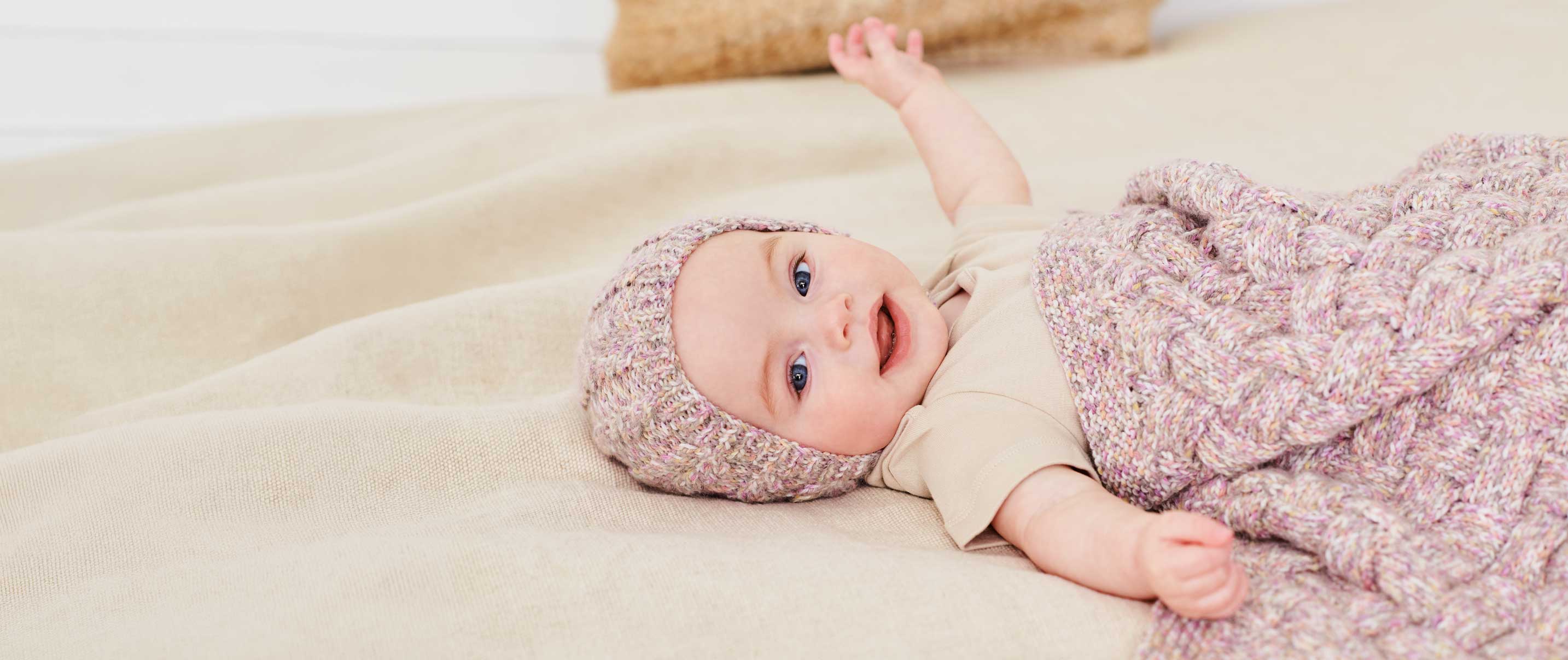 Baby mit Strickmütze und gestrickter Babydecke