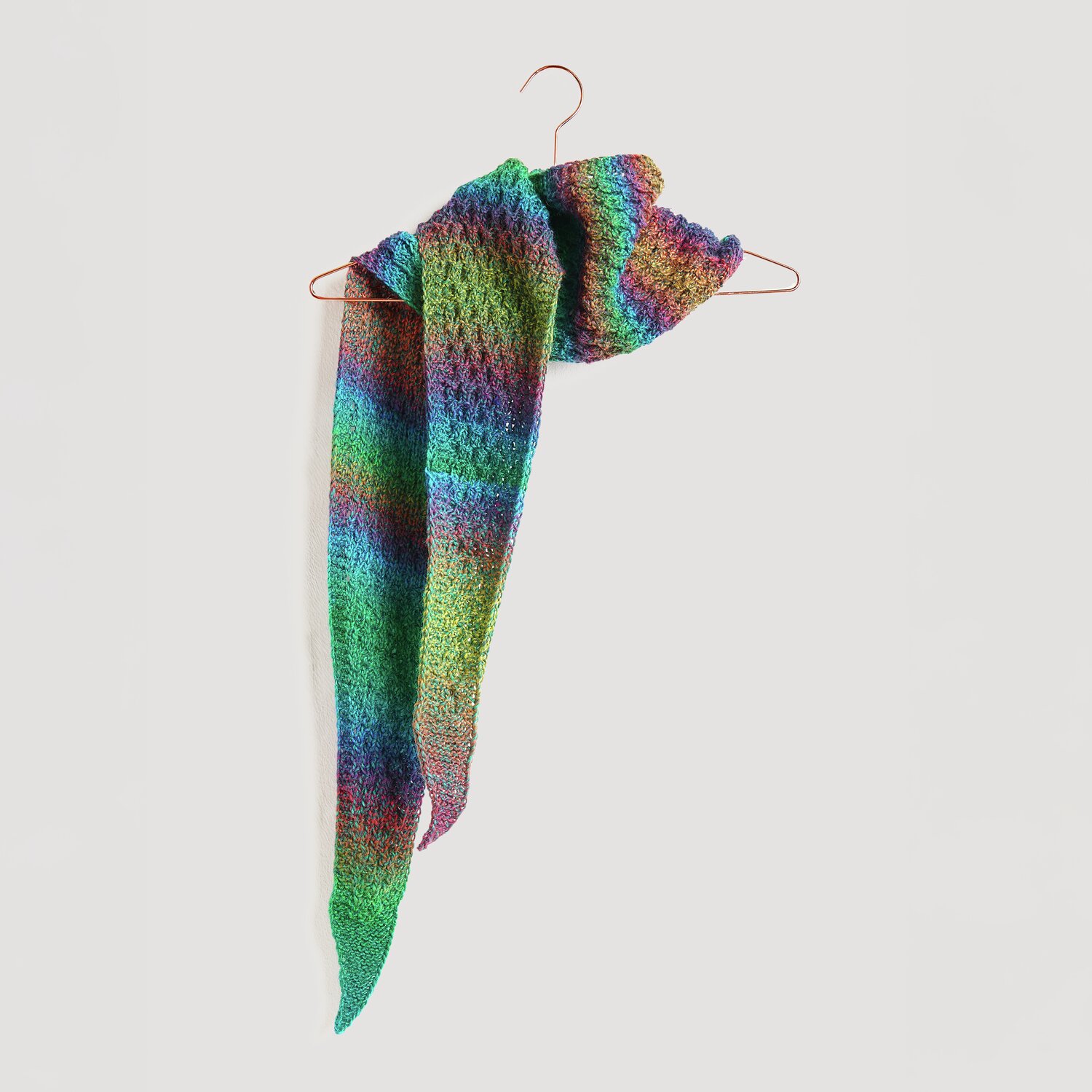 Strickset Dreieckstuch Modell 28 aus Die Neue Masche No. 13, bunte Farbverläufe, aufgehängt.