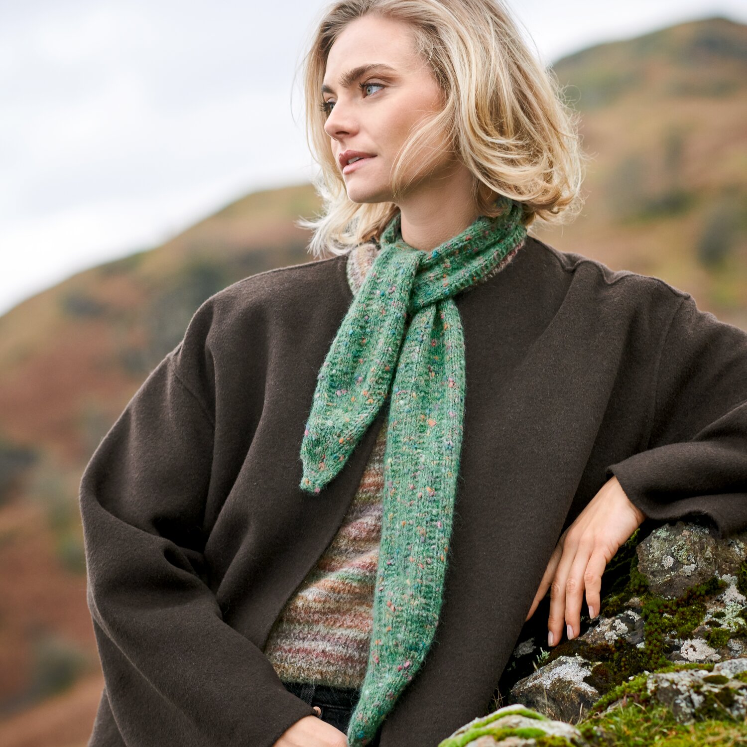 Strickset Tuch Modell 11 aus Lovewool No. 23, leichtes Stricktuch in meliertem Grün, locker um den Hals einer Frau getragen, Outdoor-Aufnahme in herbstlicher Berglandschaft