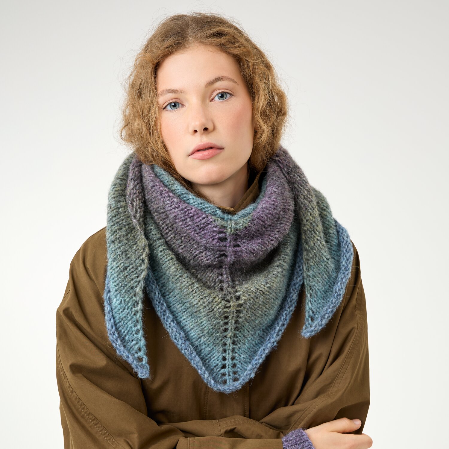 Strickset Dreieckstuch Modell 23 aus Die Neue Masche No. 16, voluminöses, mehrfarbiges Stricktuch in kühlen Tönen, getragen von junger Frau vor neutralem Hintergrund