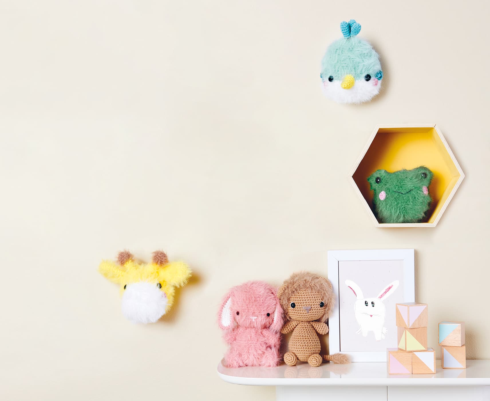 Gehäkelte Tiere mit flauschigem Fell sind an einer Wand und auf einem Regal dekoriert.