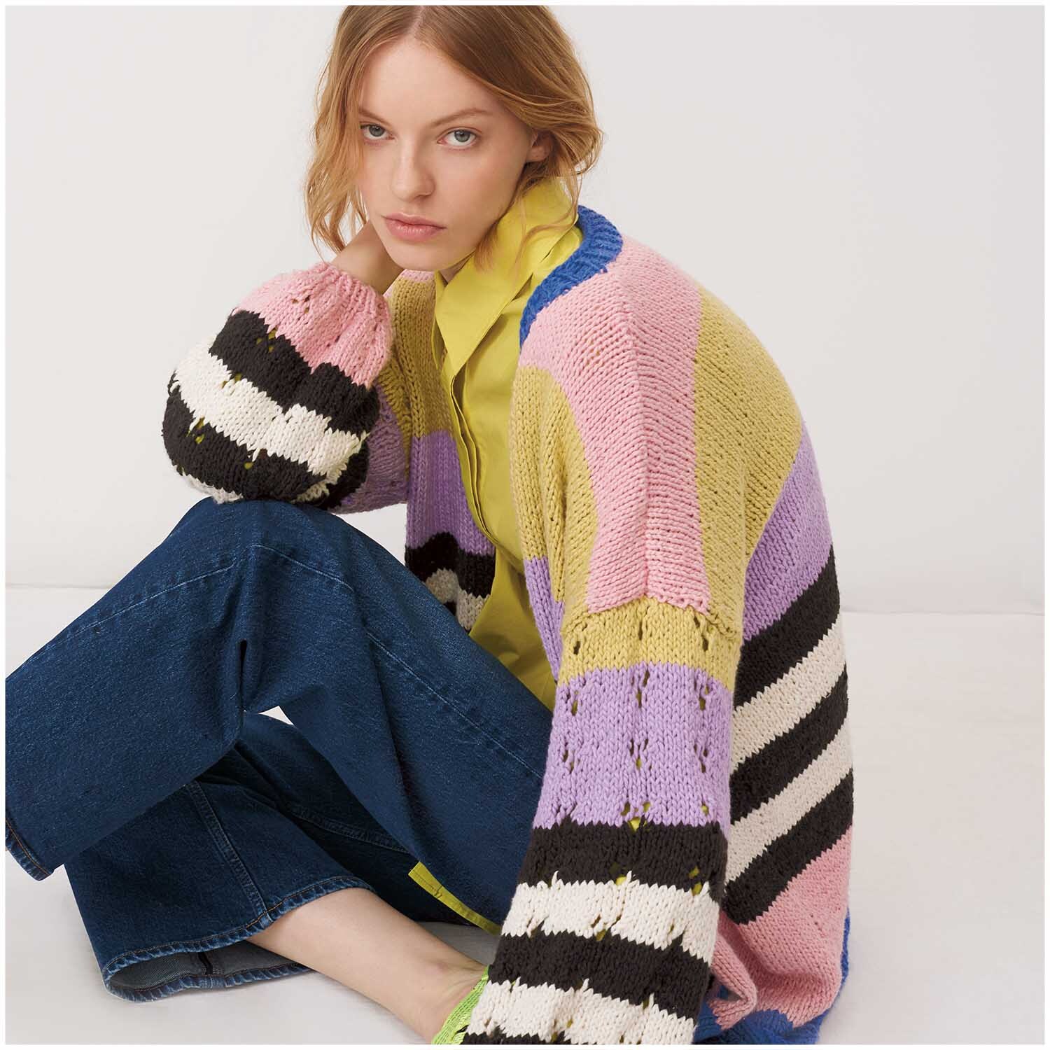 Creative So Cool + So Soft Cotton chunky: Frau in bunter Strickjacke von Rico Design, sitzt lässig auf dem Boden.
