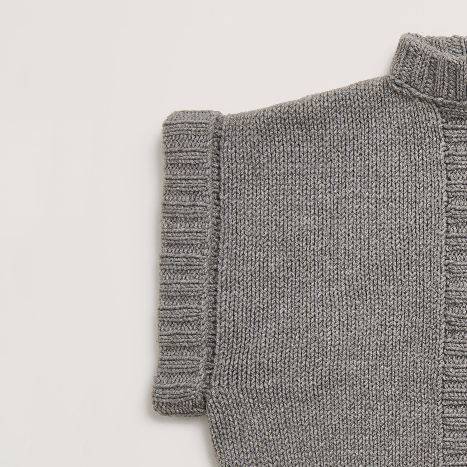 Die Neue Masche No. 14 Winter von idee. Creativmarkt Classik Pullover-Detail in Grau-Melange, gestrickt aus Wolle Rödel, zeigt feine Rippstruktur.